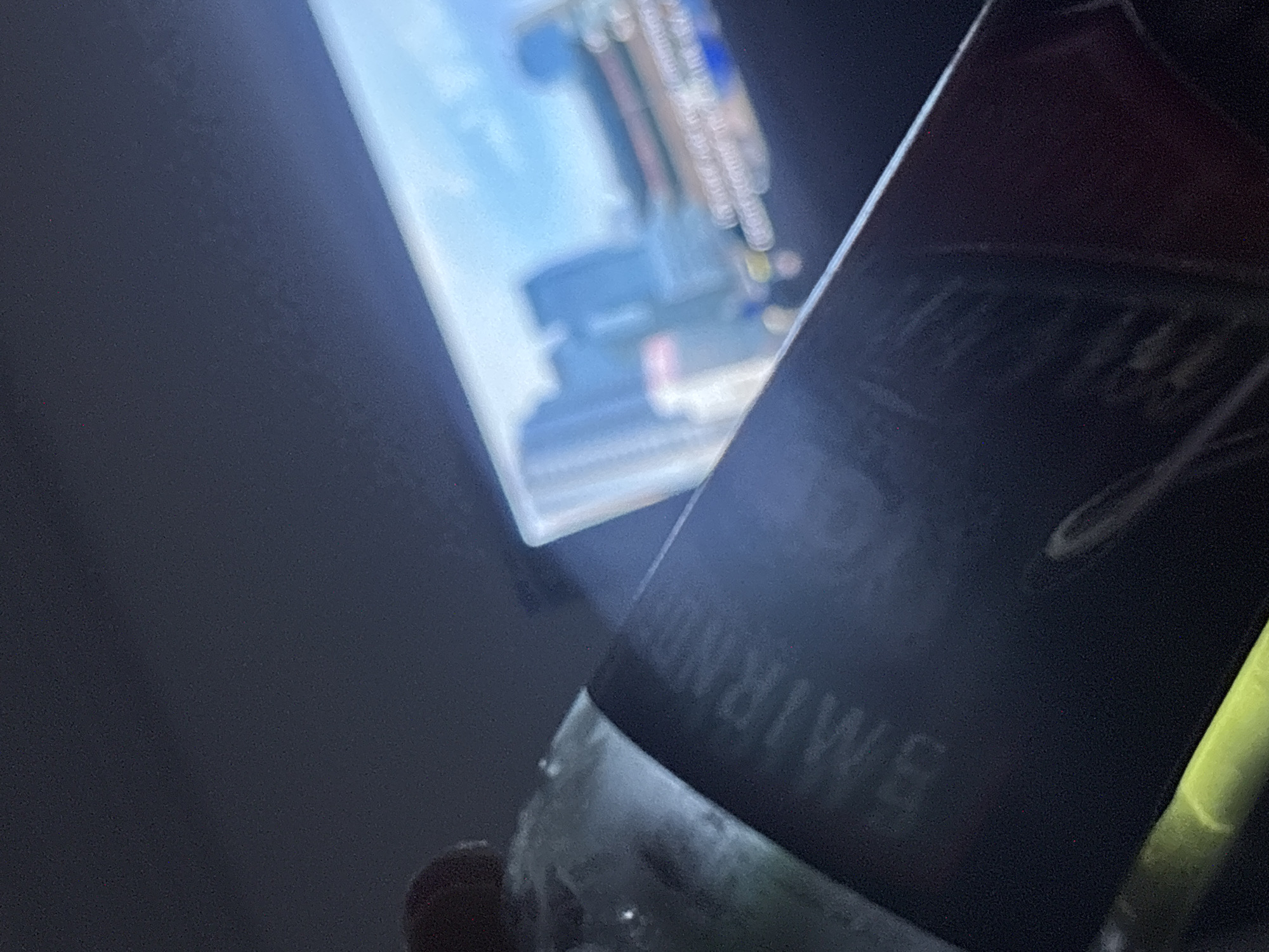 The image shows a partial view of a Smirnoff Ice bottle in the foreground. The label is partially visible with the word "SMIRNOFF" recognizable. The bottle appears to be cold and possibly frosted. In the background, there is a blurred image of a screen displaying what seems to be an urban landscape or a cityscape, possibly showing a road or building details, but the details are too indistinct to precisely identify. There is no discernible evidence that the image was taken in Port Harcourt, Nigeria. There are no people visible.