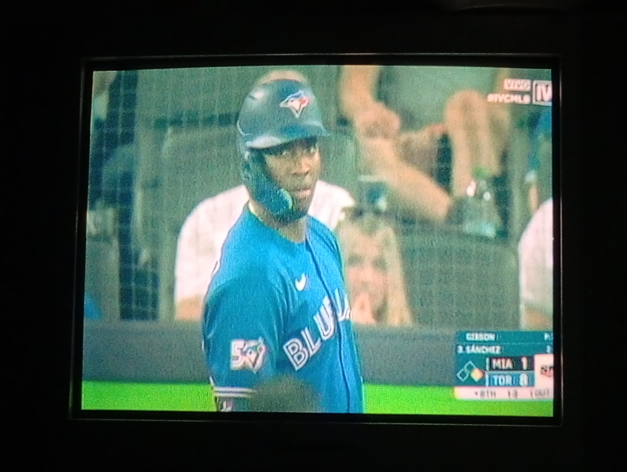A screen displays a baseball game between the Miami Marlins and the Toronto Blue Jays. The Blue Jays are at bat in the 8th inning and are winning 8-1. A Blue Jays player is at bat wearing a blue uniform with the team's logo and the number 57 on the sleeve. The game is being broadcast on IVC MLB. The image does not show any information about the city of Juan Griego, Venezuela.