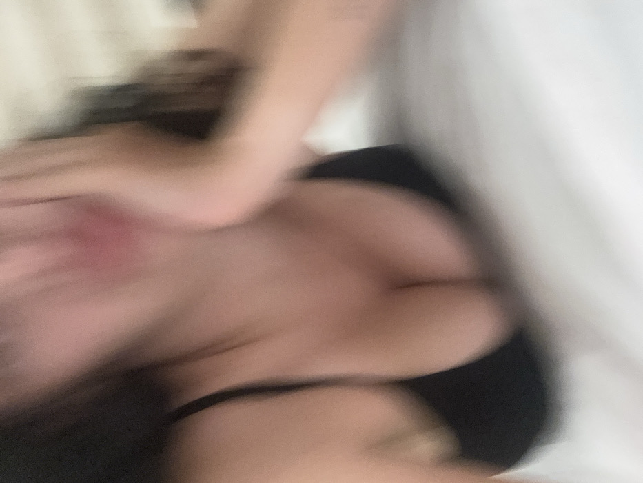 The image is heavily blurred with significant motion blur, making it difficult to discern specific details clearly. It appears to be a close-up shot, likely of a person's upper body or torso.
**What is shown in the image/video (people, objects, scene, setting):**
The primary elements visible are abstract forms created by blurred skin tones, dark shapes, and lighter backgrounds.
* **People:** There are strong indications of human skin, particularly in the central and left portions of the image, displaying shades of pink and light brown. While no facial features are visible due to the extreme blur, the forms suggest a human body.
* **Objects/Clothing:** Dark, curved shapes are noticeable in the middle-right and bottom-right sections. These shapes are consistent with what could be dark clothing, such as a bra strap or underwear, against skin.
* **Scene/Setting:** The background elements on the right and top-right are lighter, appearing as white or very light grey, which could be bedding, a sheet, or a plain wall. The overall softness and colors suggest an indoor, possibly intimate or relaxed setting, like a bedroom.
**The activity or event taking place:**
Due to the extreme blur, no specific activity or event can be definitively identified. The motion blur suggests movement, but whether it's deliberate action, incidental movement during photography, or even just camera shake is impossible to tell. The arrangement of the blurred forms hints at a person lying down or leaning.
**Notable details:**
* **Motion Blur:** The most striking characteristic is the pervasive motion blur, which smears colors and shapes across the frame.
* **Reddish Mark:** On the central-left area, within the skin-toned regions, there is a distinct reddish or pinkish patch. Its nature is unclear due to the blur; it could be a mark on the skin (like a bruise, rash, or hickey) or merely a color artifact from the blurring process.
* **Intimate scale:** The close-up nature of the shot suggests a personal or intimate moment.
* **Lighting:** The lighting appears soft and indirect, contributing to the gentle tones of the skin and background. No harsh shadows are visible.
**Any text visible in the image/video:**
No text is visible in the image.