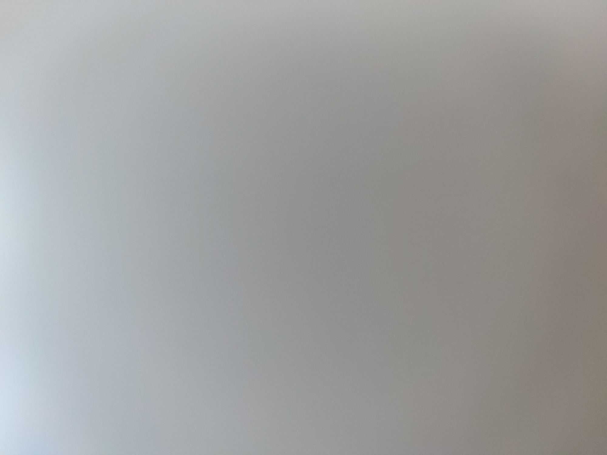 The image is a blurry, out-of-focus shot of a gray surface. There are no discernible people, subjects, or objects present. The location is unknown.