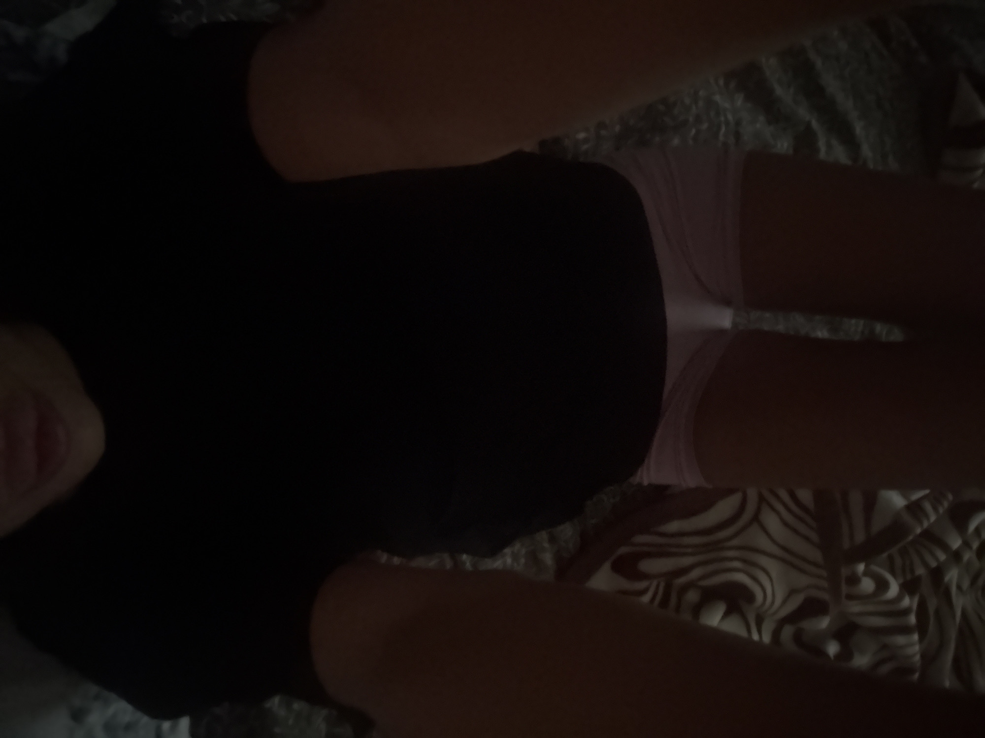 The image shows a person lying on their back, facing upwards. The person is wearing pink underwear and a black top. Their legs are raised and bent at the knees. The background appears to be a bed with a patterned blanket. There is no indication of the location being in the city of Basarabeasca, Moldova.