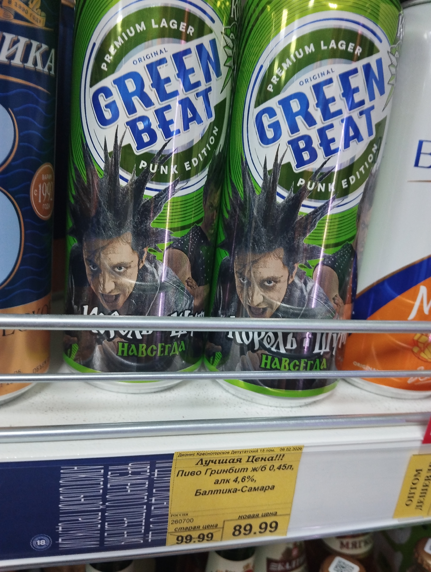 The image shows two cans of "Green Beat Punk Edition" beer on a shelf. The cans are green and feature a punk-themed design with a person with a mohawk. A price tag is visible below the cans, displaying a promotion in Russian for "Green Beat" beer, noting it's a 0.45-liter can, 4.6% alcohol, produced by Baltika-Samara. The sign indicates the location is Krasnogorskoye, Russia.