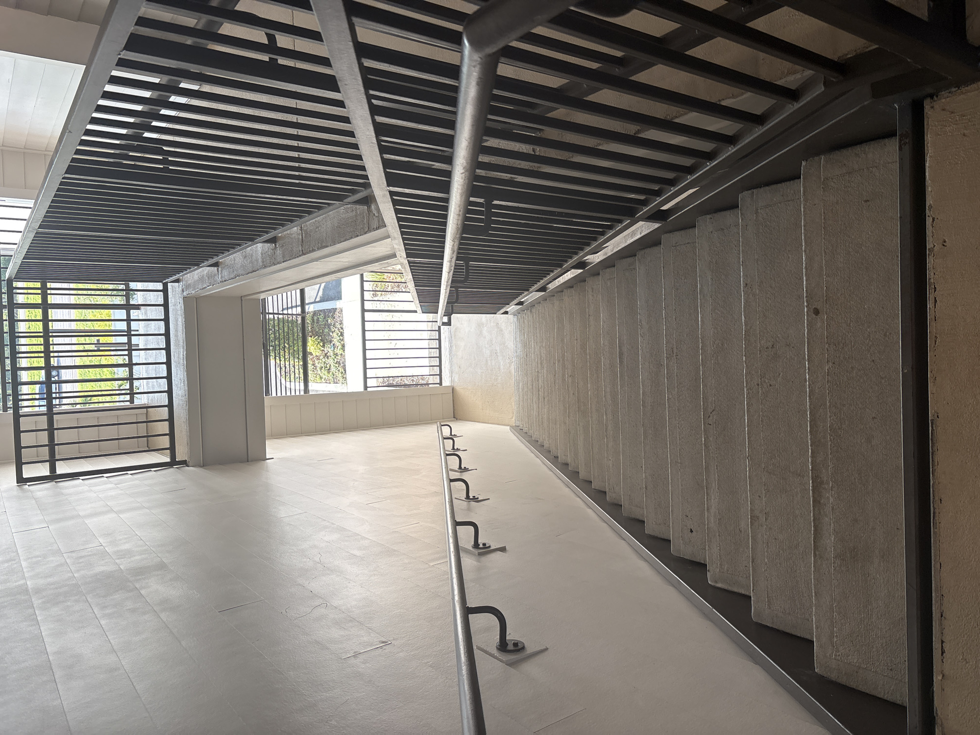 The image depicts an outdoor concrete staircase with black metal railings on both sides. The staircase leads downwards, with multiple steps visible. The walls beside the stairs are painted a light color, with one side featuring a handrail attached by curved brackets. The scene is illuminated by natural light, suggesting it is daytime. The location is identified as Palmetto, United States. There are no people visible in the image, and the focus is on the architecture of the stairwell.