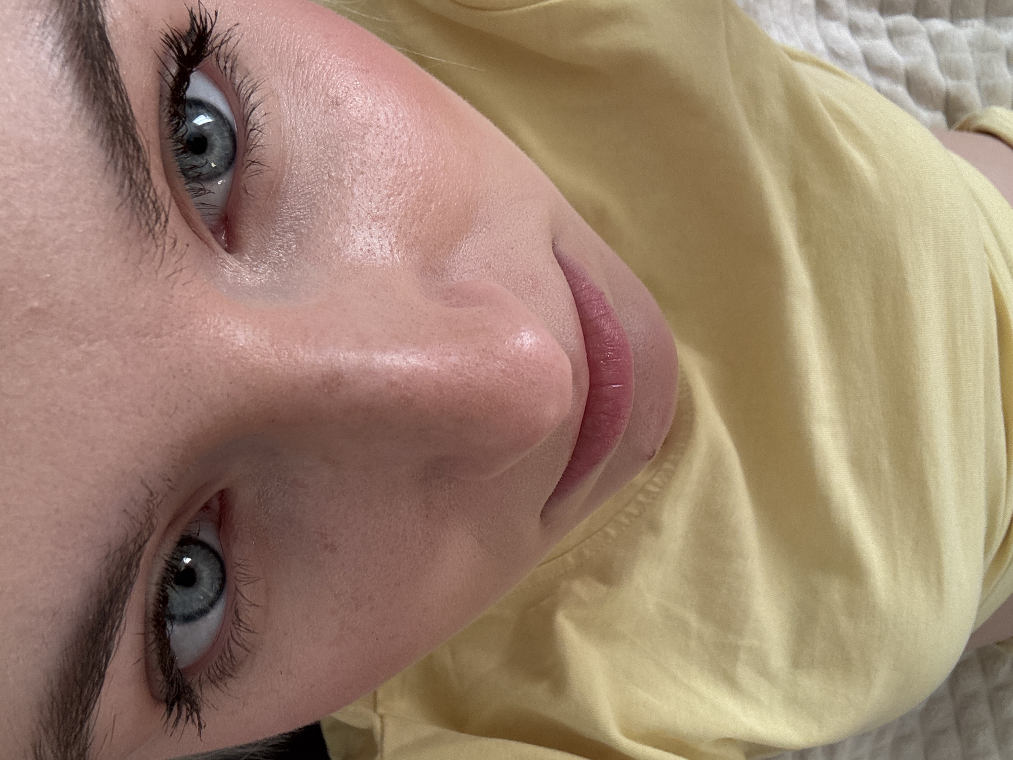 A close-up, rotated image shows a fair-skinned person with blue eyes and prominent eyebrows. The person is wearing a yellow garment. No location information is discernible from the image.