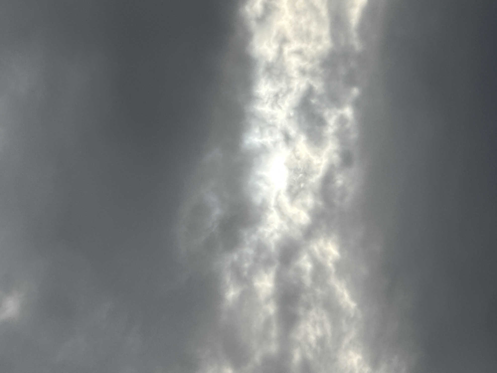 The image shows a cloudy sky, likely an overcast condition. There is a brighter, vertical band of lighter clouds, suggesting a break in the denser cloud cover where sunlight might be filtering through. The overall color palette is predominantly grey.
It is not possible to determine the location within the city of Nizhny Novgorod, Russia or any other specific location. There are no people, subjects, objects, actions, or interactions visible in the image.
