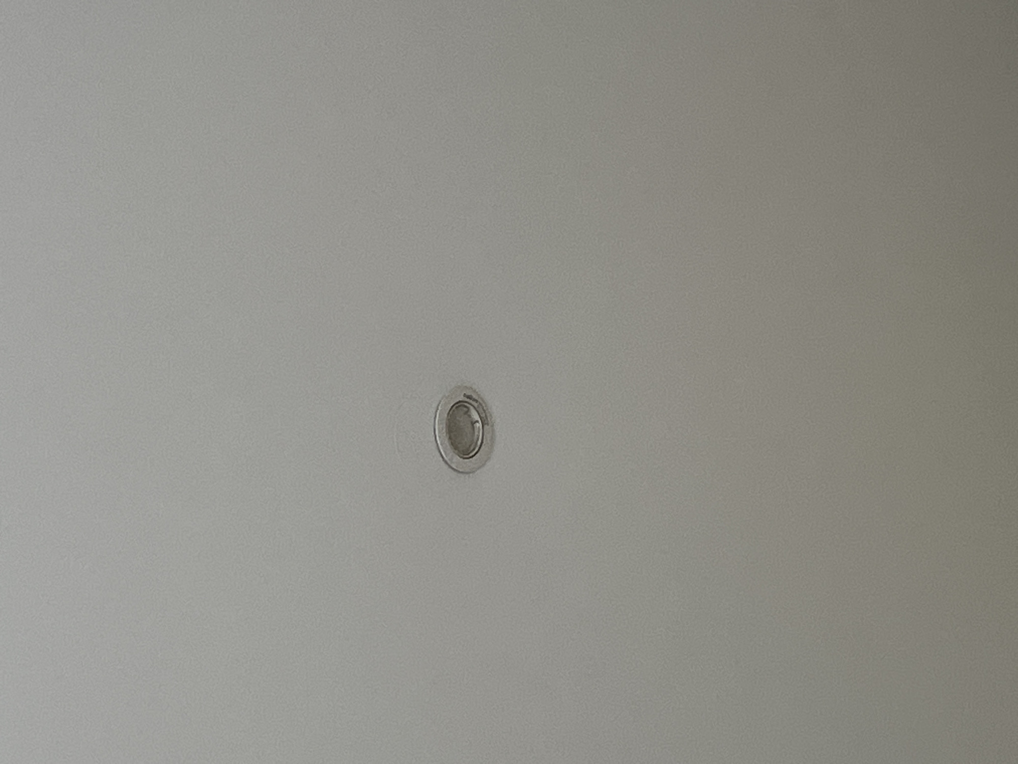 The image shows a single recessed light fixture on a textured, off-white ceiling. The light fixture is circular with a metallic trim and appears to be recessed into the ceiling material. No other objects or people are visible in the frame. The lighting is even, suggesting ambient light rather than direct illumination from the fixture itself. The image is taken from a low angle, looking upwards at the ceiling. The location in Chelyabinsk, Russia, is not discernible from the visual information present in the image.