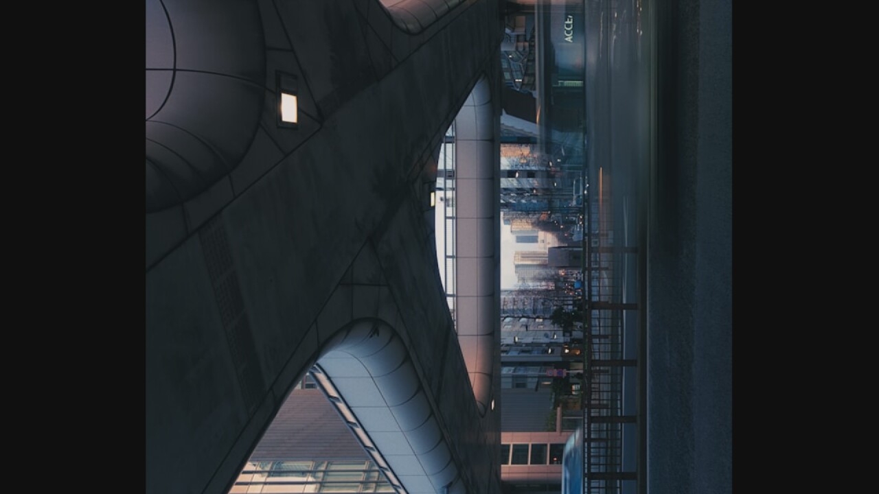 The image shows a low-angle view of an elevated pedestrian walkway or overpass in a city, likely during dusk or dawn. The walkway is constructed of concrete and metal, with a curved, modern design. Below the walkway, a street is visible with traffic, indicated by blurred streaks of light from vehicles. Buildings line the street, appearing to be a mix of commercial and residential structures. The sky transitions from a muted pink and orange near the horizon to a deep blue overhead. A sign with the partial text "ACCE" is visible on one of the buildings. The overall atmosphere is one of urban activity and infrastructure. The location is not Oreshki, Russia.