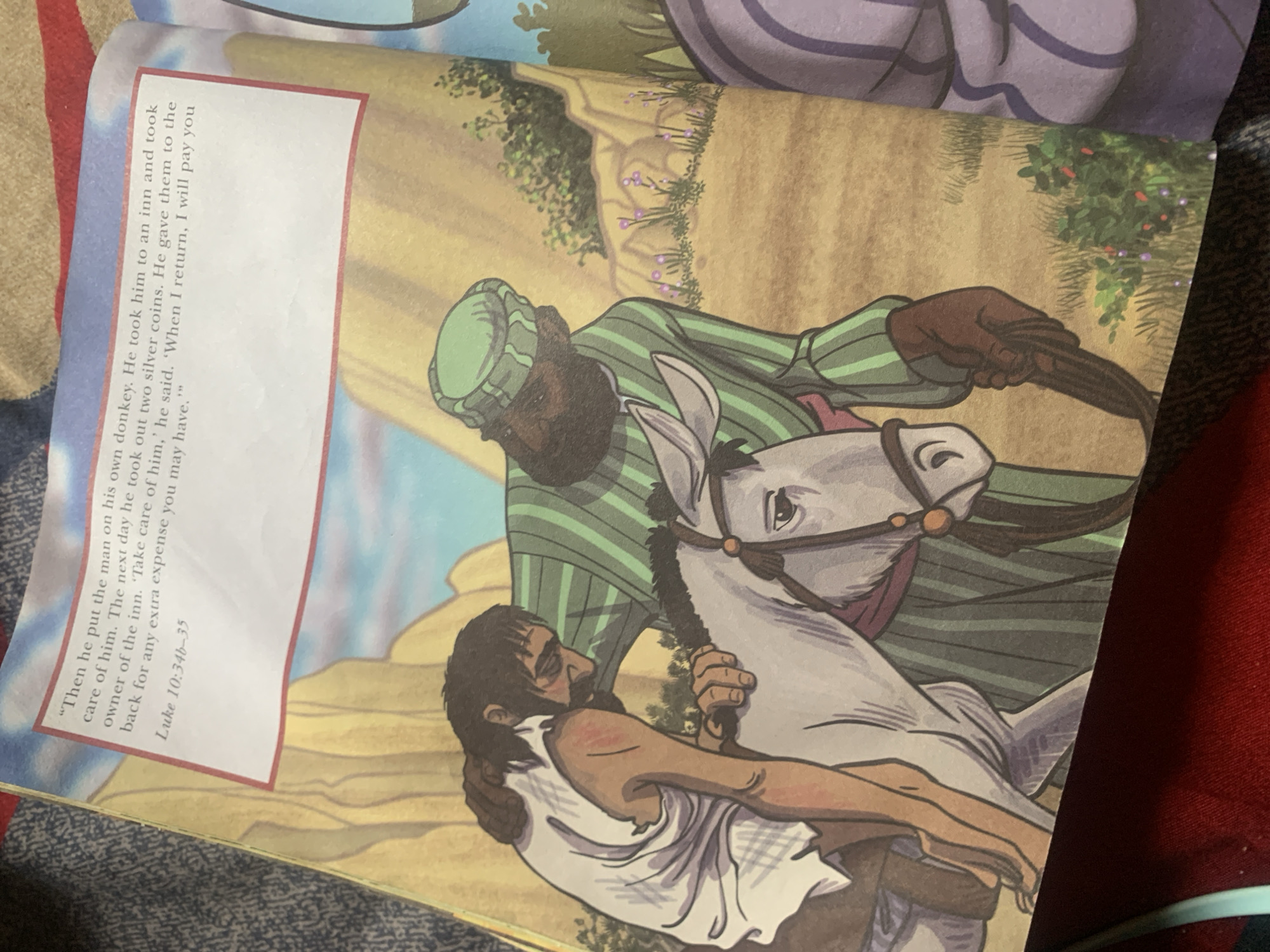 The image is a page from a children's book, featuring an illustration and text. The illustration depicts a man, dressed in a white, tattered garment, being helped onto a donkey by another man wearing a green and white striped robe and a green turban. The man in white appears injured or ill. The background suggests a rocky, arid landscape with some sparse vegetation. The text, located in the upper left corner, is a quote from Luke 10:34b-35, detailing a story of a traveler being cared for. There is no depiction of Jauro Yinu, Nigeria, nor any elements that would suggest this specific location.