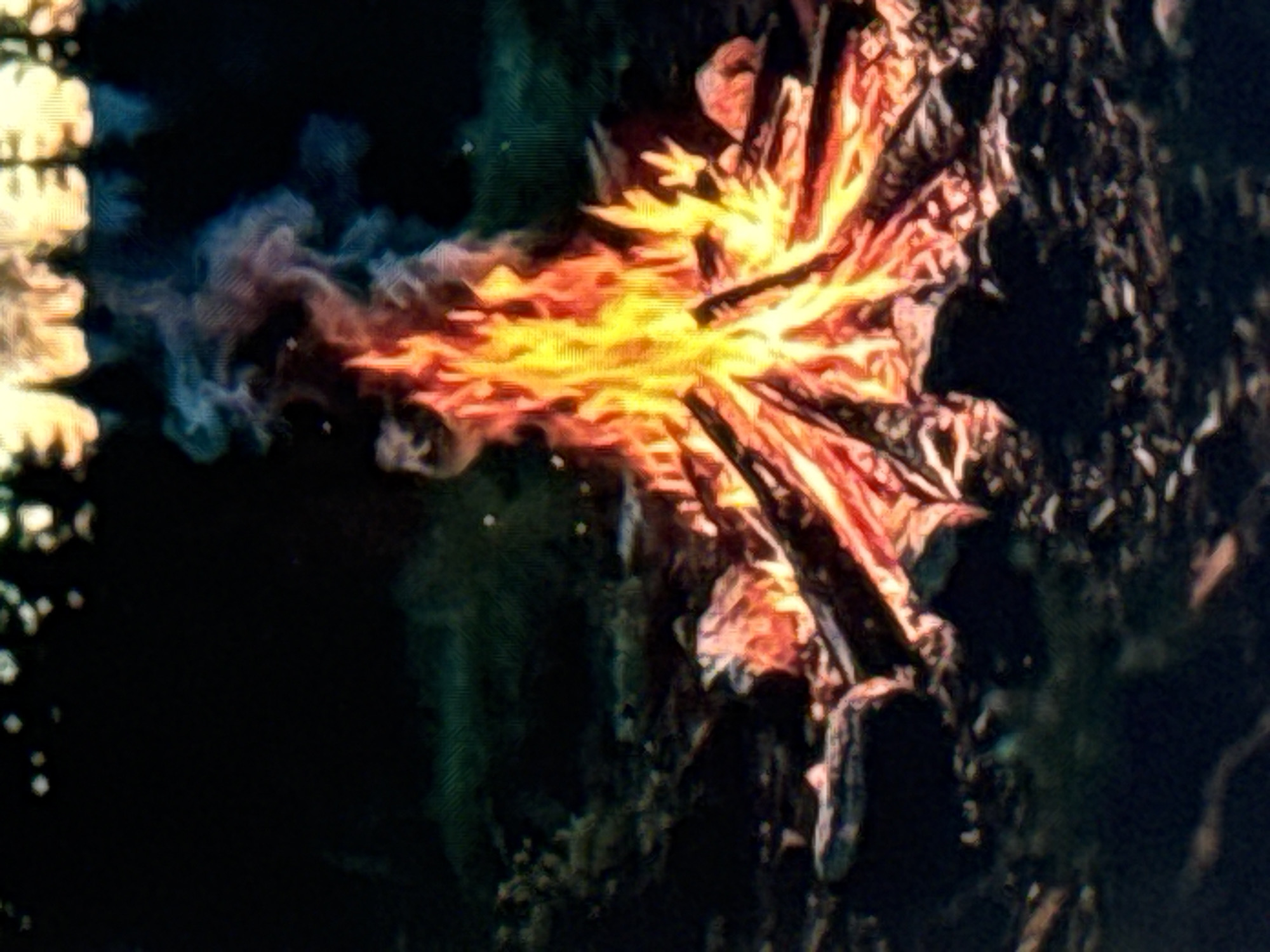 A campfire burns brightly in a dark, natural setting, likely at dusk or night. The fire is composed of logs arranged in a tepee formation, emitting a warm, orange and yellow glow. Wisps of pale blue and pink smoke rise from the flames and drift upwards into the darkness. The ground surrounding the fire is covered in small stones and debris. In the background, the silhouettes of trees are visible against a dimly lit sky, suggesting a forest or wilderness environment. There are no people visible in the image. The image quality is somewhat grainy and appears to be a photograph or a digital rendering. There is no information to suggest the location is in the city of Norilsk, Russia.