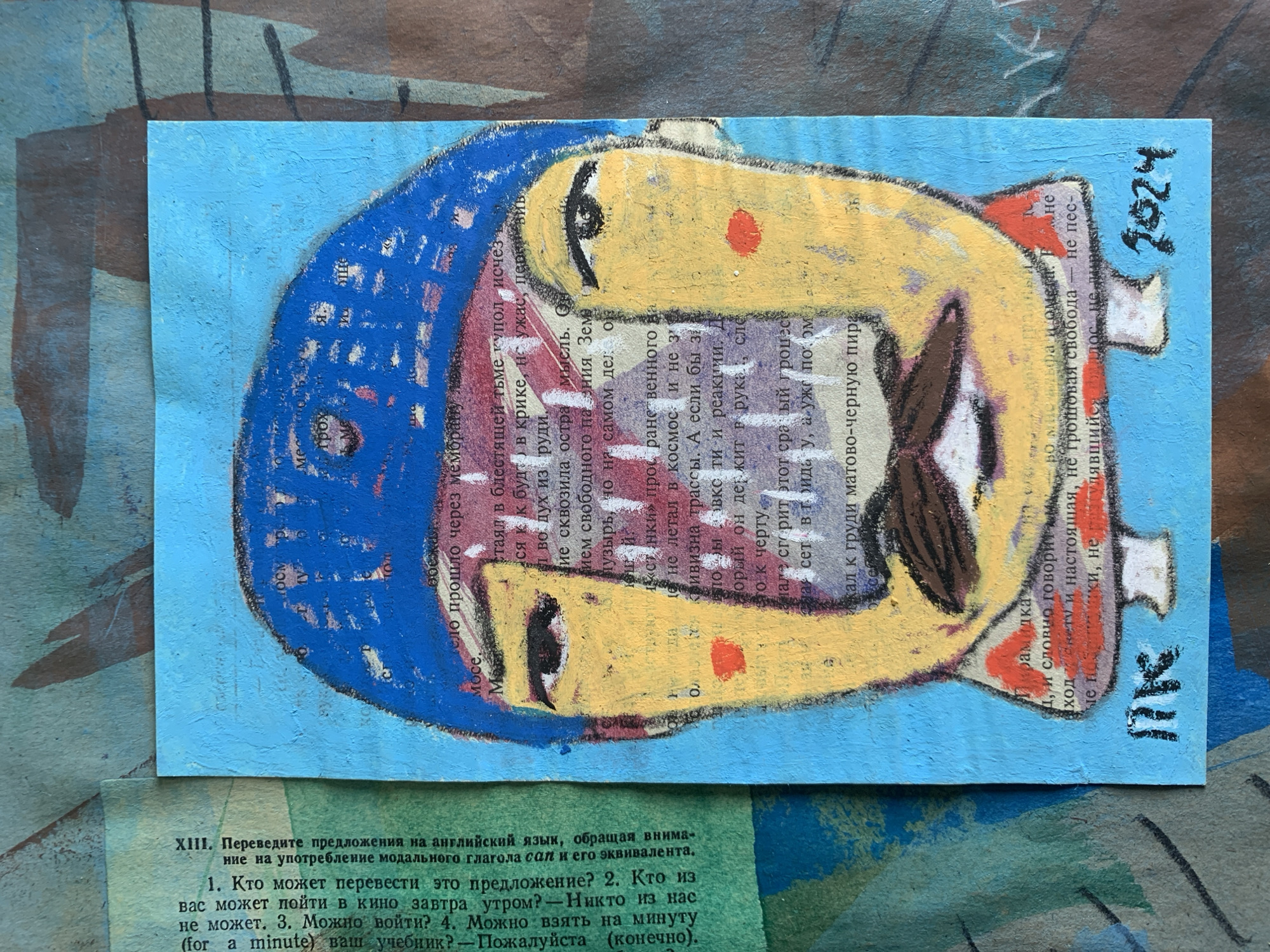 The image is a close-up, eye-level, horizontal shot of a collage artwork on a light blue paper background, which is itself layered on top of other textured paper materials in muted earthy tones. The artwork is a portrait of a person's face, rendered in a stylized, almost naive manner with bold outlines and vibrant colors.
The subject of the artwork has yellow skin, a blue cap or hat covering their head, and dark eyebrows. Their eyes are dark and almond-shaped, with one eye slightly more prominent. There are two red circles on the cheeks, suggesting blush or rosy cheeks, and a dark brown mustache above the mouth. The mouth is a thin, dark line. The figure is wearing a red and white collar.
The artwork is created on a background of text from a book or newspaper, visible through the paint, particularly on the face and parts of the head. There is a signature or monogram in black marker at the bottom left, appearing as "ПК" or "MK," and a date, "2024," in black marker at the bottom right. The artwork's textured surface suggests the use of pastels or crayons over paper and possibly some form of mixed media.
The surrounding background materials have a rough, textured appearance with abstract shapes and dark lines. The overall impression is of a handmade, expressive piece of art.
There is no information in the image to suggest a location in Sergeevo, Russia, or any other specific city.