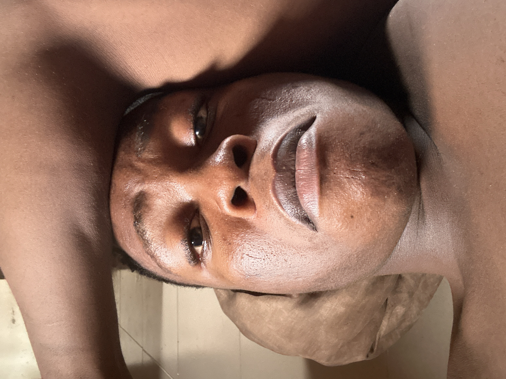 A close-up image of a person with dark skin. The person is lying on their back. The scene's location in Ikorodu, Nigeria, cannot be determined from the image.