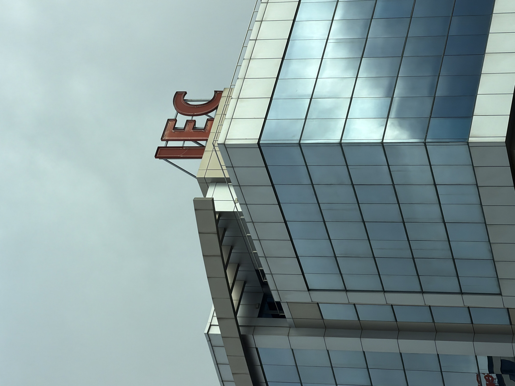 The image shows the Interpred World Trade Center Sofia building in Sofia, Bulgaria. The building is a modern, high-rise structure with a glass and steel facade. The red "IEC" sign is visible on the roof of the building. The sky is overcast.