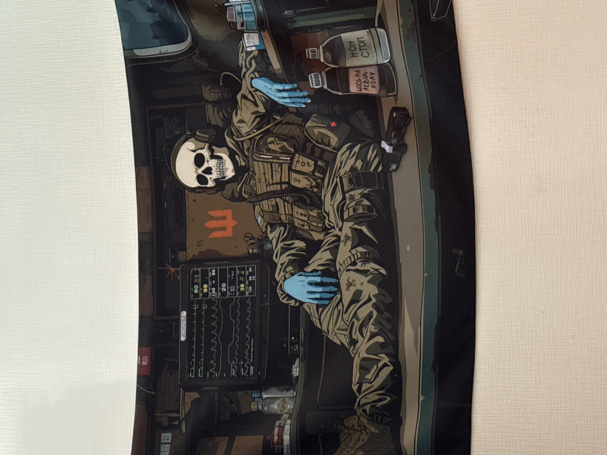The image is a close-up of a digital illustration depicting a skeleton in military attire, wearing headphones and blue medical gloves. The skeleton is seated, with its legs crossed, in what appears to be a vehicle or confined space. In front of the skeleton is a medical monitor displaying vital signs and waveforms. To the left of the monitor are two bottles, one with a red cap and the other with a white cap, both containing liquid. To the right of the skeleton, on a surface, are two more bottles, one labeled in Cyrillic script. A handgun lies on the surface in front of the skeleton. The background shows elements of military equipment and a symbol resembling a trident. The overall scene is dark and appears to be set within a military context, possibly a medical unit or command center. There is no explicit indication of the city of Kharkiv, Ukraine, in the image.