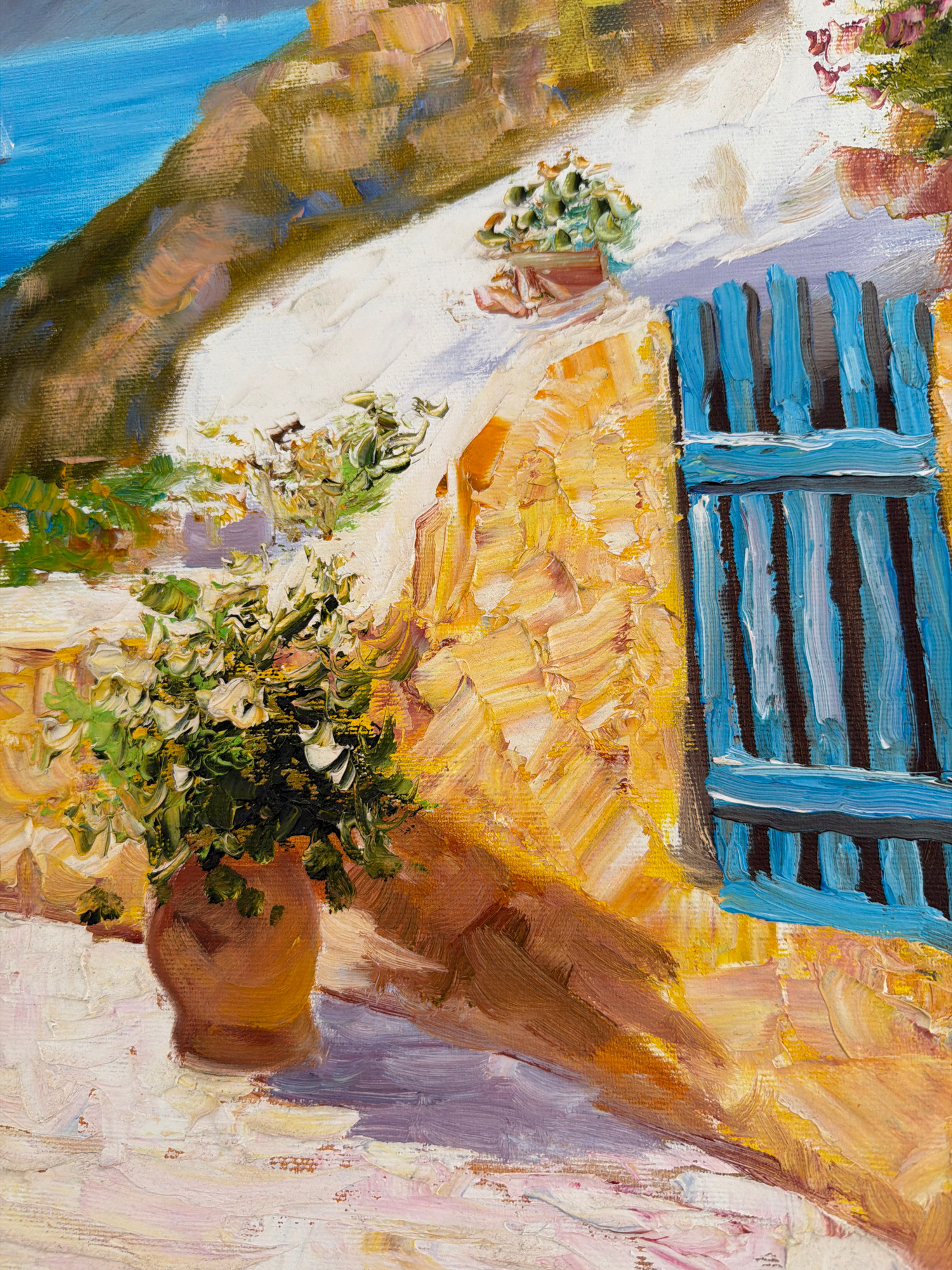 This is a close-up oil painting of a building with blue shutters and a potted plant. The building's facade is textured with thick impasto strokes of yellow and orange paint. The blue shutters are vertical and detailed with darker lines suggesting shadow. A terracotta pot with abundant green and white foliage sits on a textured, light-colored surface in the foreground, casting a shadow. In the background, a slope covered in vegetation leads to a bright blue body of water. The style is impressionistic, focusing on light and texture. There is no indication of the city of Kyiv, Ukraine, or any people in the image.