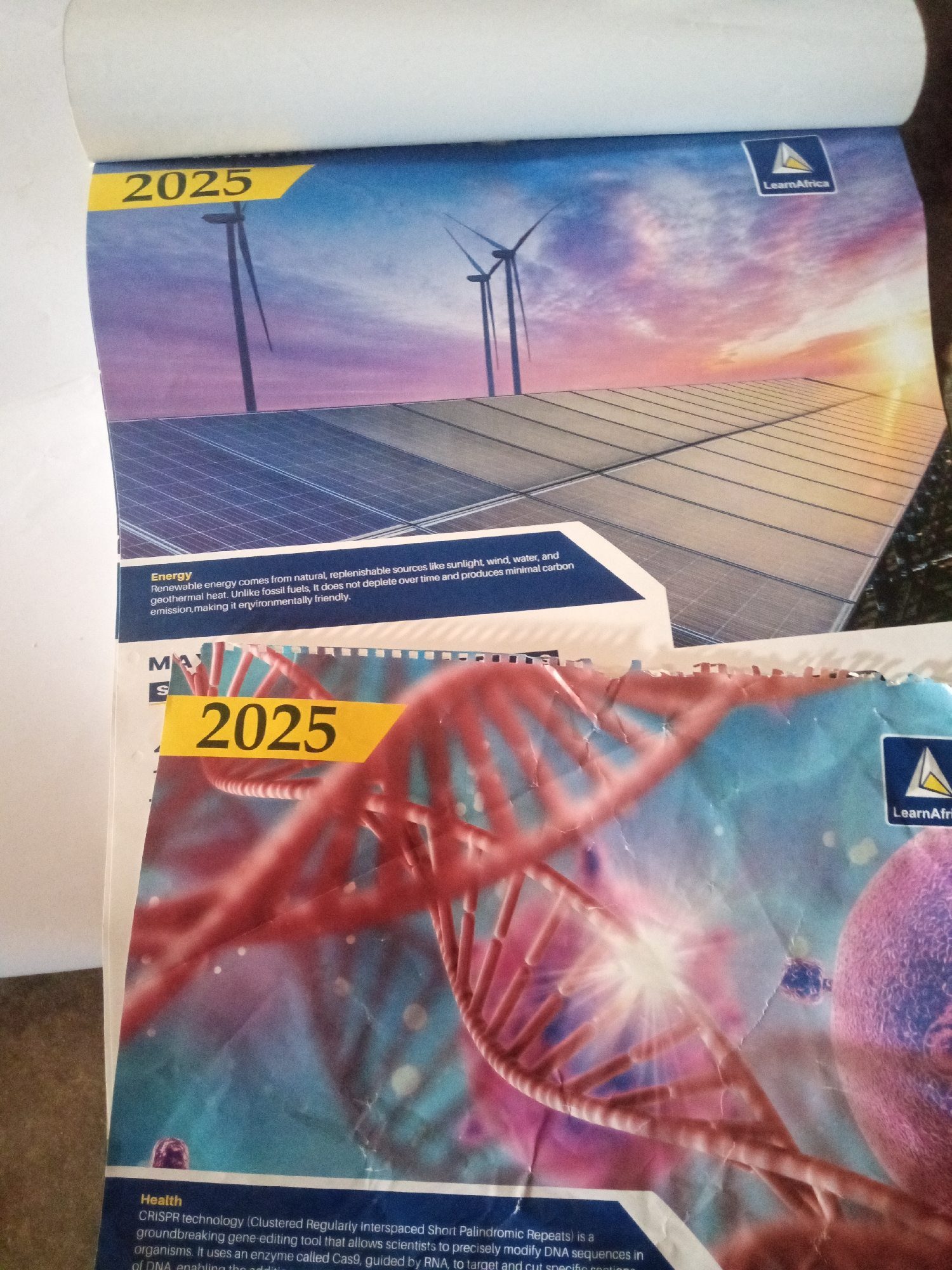 This media file shows two pages of a calendar from Jalingo, Nigeria, both featuring the year 2025. The top page displays a serene sunset scene with wind turbines and solar panels, symbolizing renewable energy. The text below the image describes renewable energy sources, highlighting their natural origins and environmental benefits, and includes the "LearnAfrica" logo. The bottom page shifts focus to health and genetics, featuring a prominent illustration of a DNA double helix. The text discusses CRISPR technology, a gene-editing tool, and its applications. The "LearnAfrica" logo is also present on this page. Both pages appear to be from a calendar or educational material, likely intended for a Nigerian audience given the location context. The overall impression is one of forward-thinking themes, encompassing both environmental sustainability and advancements in scientific technology.