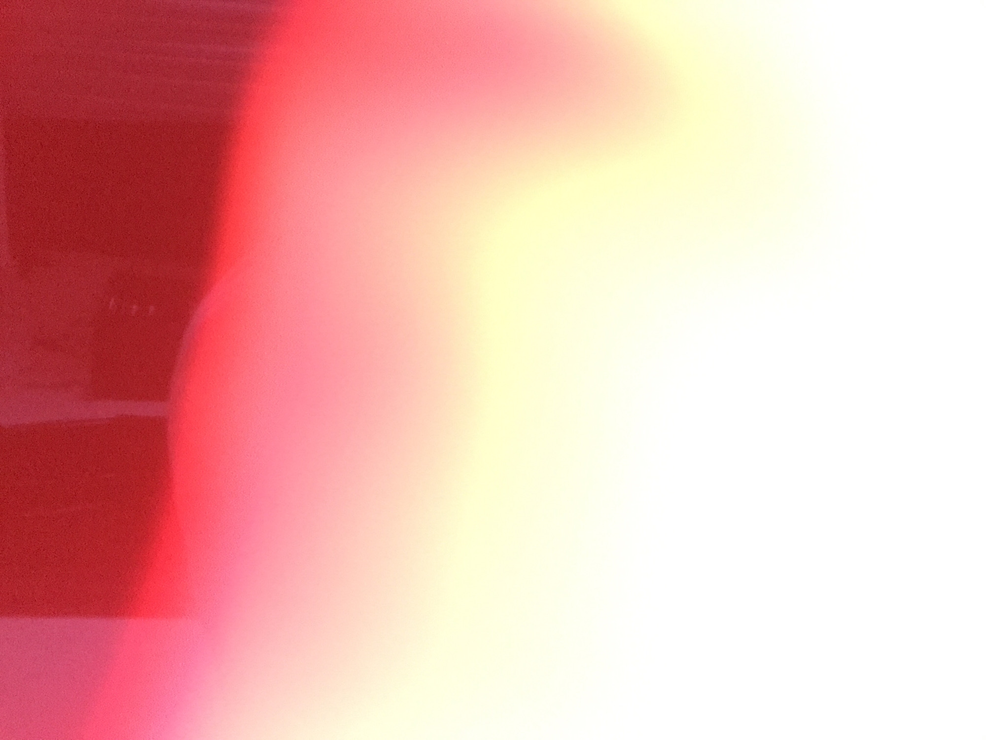 The image appears to be a blurry photograph with a red section on the left transitioning into pink and yellow towards the right, which then fades to white. There are no discernible details to identify people, subjects, objects, actions, or interactions. The environment is ambiguous due to the lack of clear details. The location in Yerevan, Armenia cannot be determined from the image.