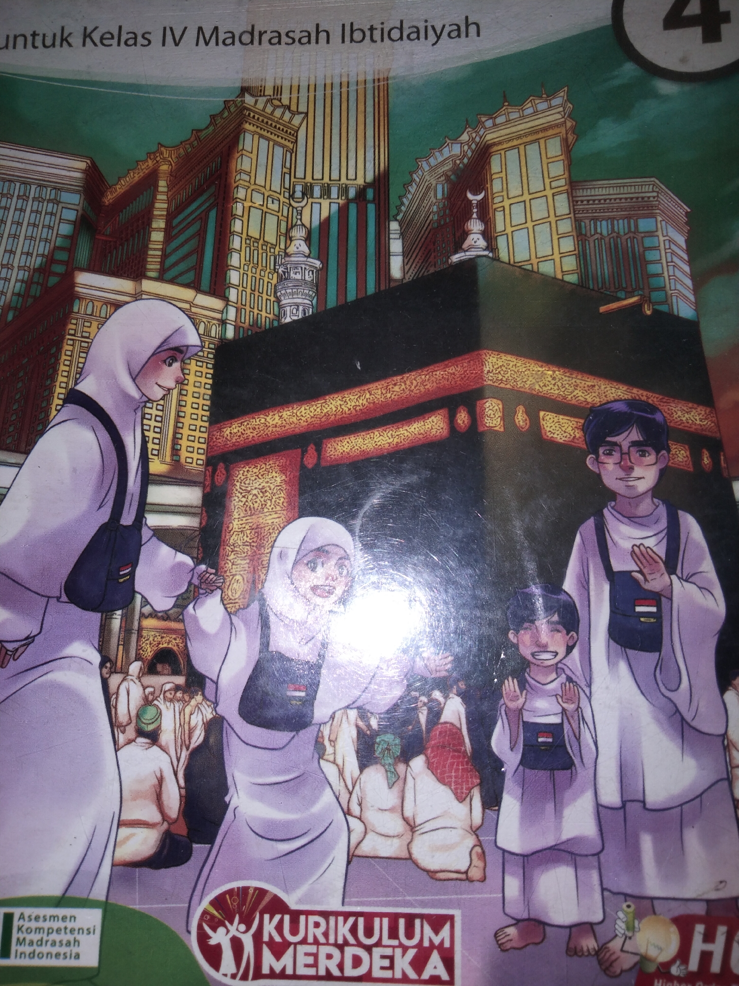This media file is a cover for a book, likely a textbook for Indonesian elementary school students (Kelas IV Madrasah Ibtidaiyah). The cover depicts a scene of people in traditional Islamic attire, likely performing Hajj or Umrah, with the Kaaba in Mecca as the central focus.
The subjects include several characters dressed in white ihram garments, some wearing hijabs. There are adults and children, all appearing to be participating in a religious pilgrimage. The Kaaba, a black cube-shaped structure, is prominently displayed, surrounded by tall, modern buildings that resemble skyscrapers, hinting at the contemporary urban landscape of Mecca. A minaret is also visible in the background.
The activity taking place is a religious pilgrimage. The people are shown in various poses, suggesting movement and interaction. Some are walking, while others are standing and observing. One adult is holding the hand of a child, indicating a family or group outing.
Notable details include the bright, somewhat hazy lighting, suggesting a daytime scene. The overall atmosphere appears to be one of reverence and possibly excitement, conveyed through the simplified, animated style of the illustrations. The expressions on the faces of the characters are generally positive and engaged.
Visible text on the cover includes:
- "untuk Kelas IV Madrasah Ibtidaiyah" (for Class IV Islamic Elementary School)
- "4" (likely indicating the class level)
- "Asesmen Kompetensi Madrasah Indonesia" (Indonesian Madrasah Competency Assessment)
- "KURIKULUM MERDEKA" (Merdeka Curriculum, a national curriculum in Indonesia)
- "H" (part of a larger logo, possibly for a publisher)
The setting is clearly identified as related to religious pilgrimage in Mecca, with the inclusion of the Kaaba and surrounding architecture. The text indicates an Indonesian context for the educational material.