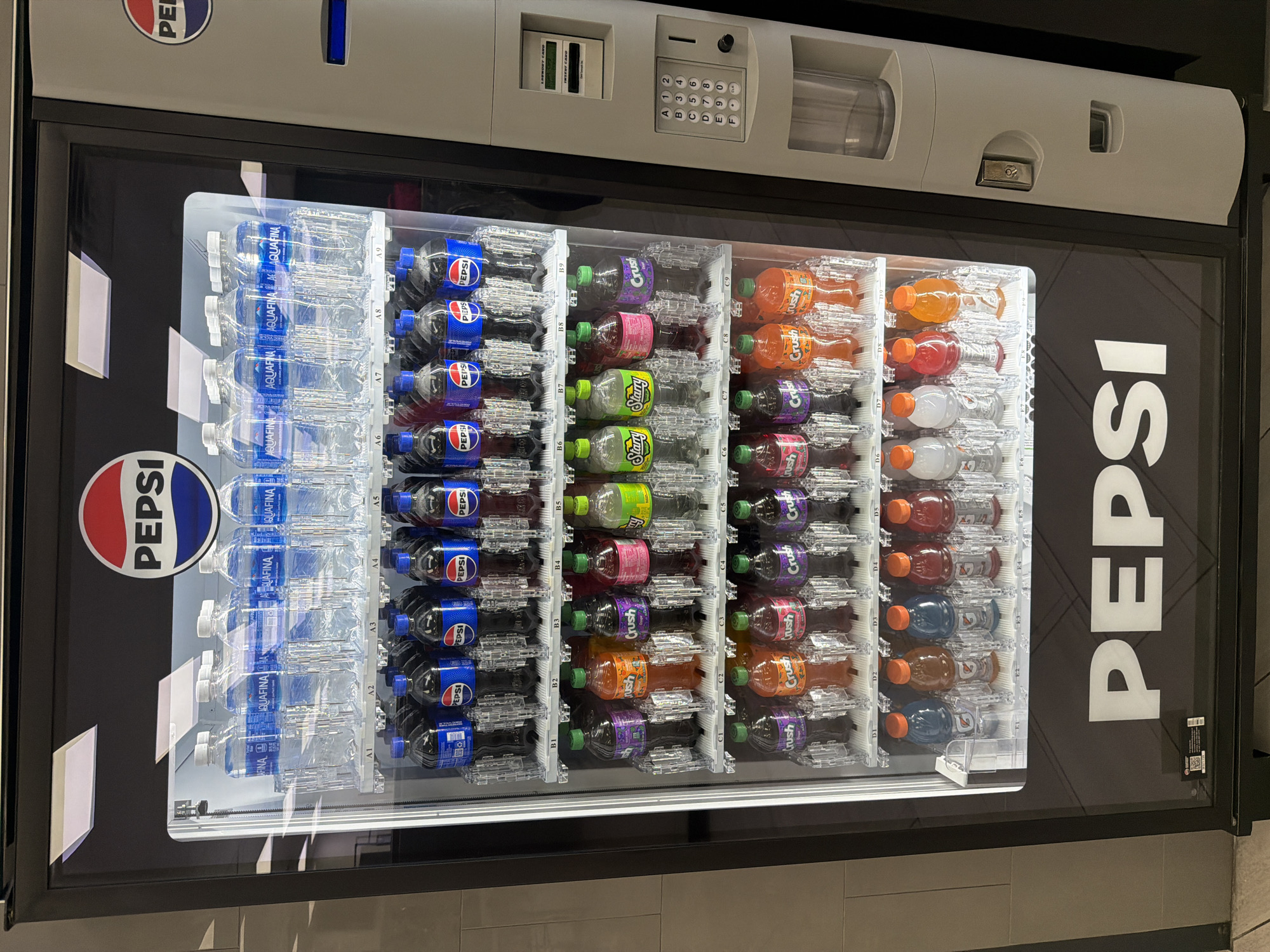 Here is a concise description of the image:
The image shows a Pepsi-branded vending machine stocked with various beverages. The machine contains Aquafina water bottles, Pepsi cola, and different flavors of Crush and Starry sodas. The vending machine has a keypad for selecting items and a slot for inserting payment. The specific location is not discernible from the image alone. Without additional information, it is impossible to verify that the machine is in Niles, United States.