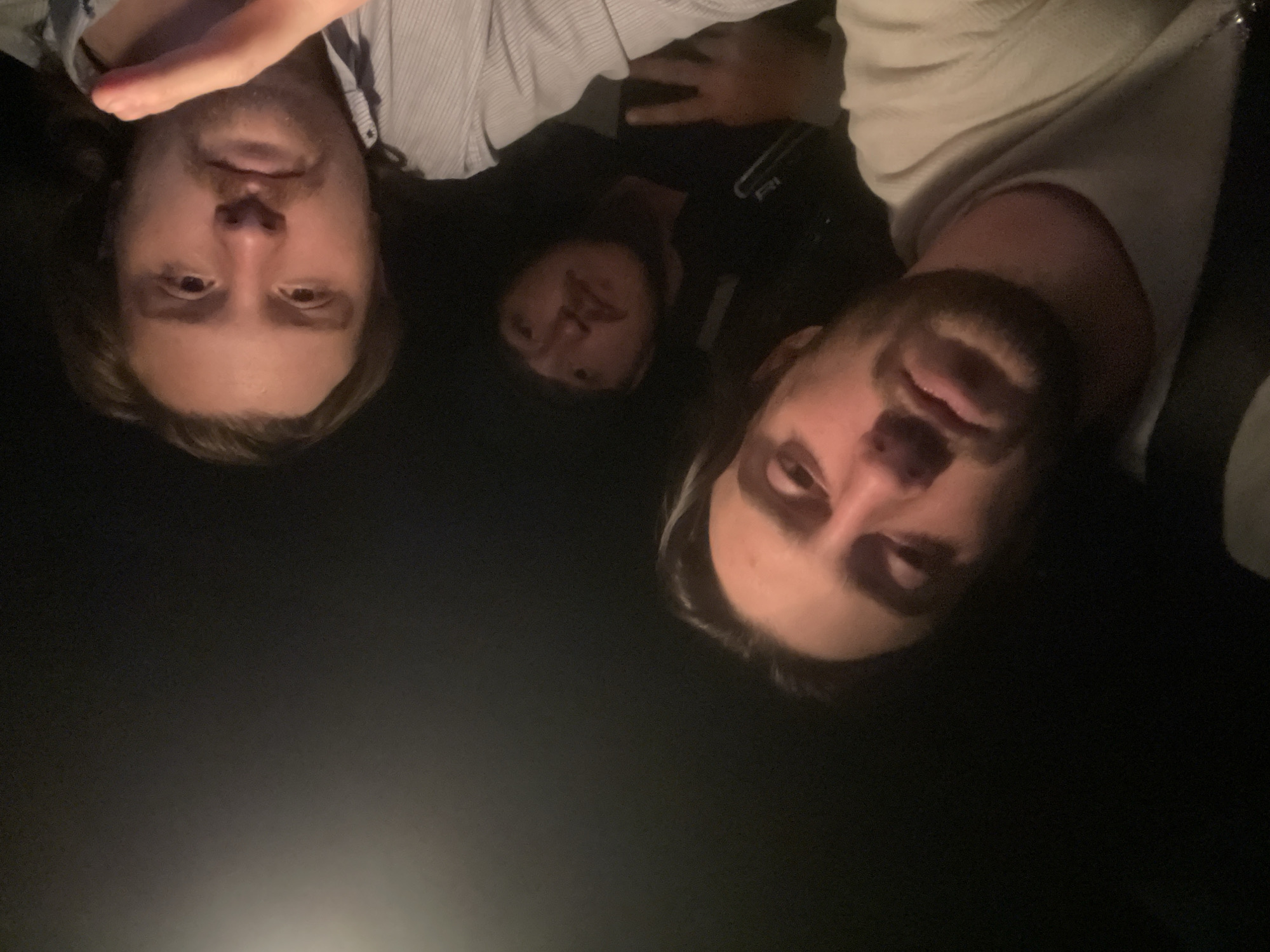 Three people are visible in the image. Two men are positioned near the edges of the frame, while a third individual is located between them. The lighting in the scene is predominantly dark. The location, Huixquilucan de Degollado, Mexico, is not evident from the content of the image.