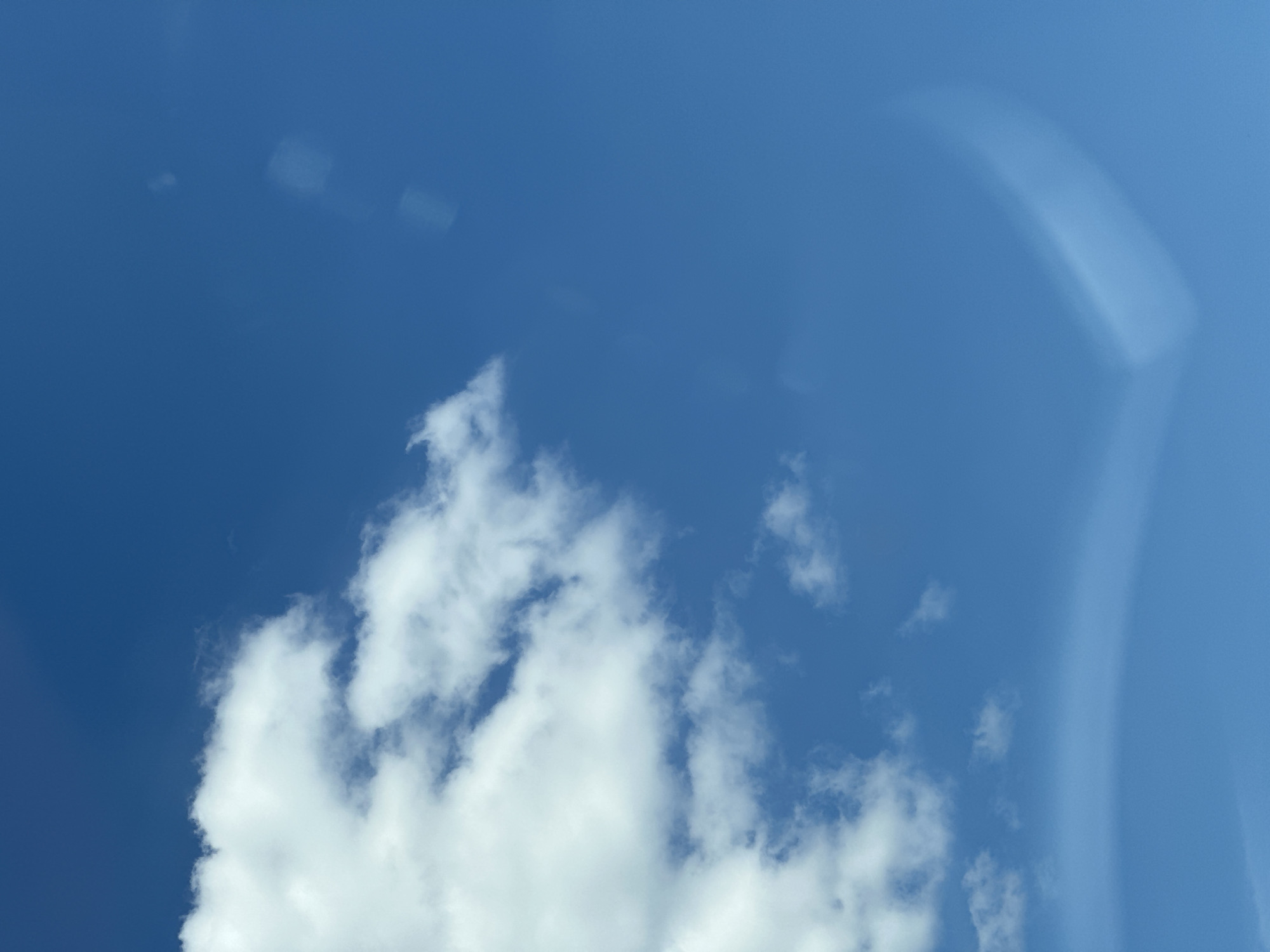 The image depicts a bright blue sky with scattered white clouds. A large, fluffy cloud formation is visible on the left side of the frame, extending towards the center. The sky is clear and sunny, with no visible landmarks or structures. The overall scene suggests an outdoor environment on a clear day. There is no information available to determine the specific location within Plesetsk, Russia.
