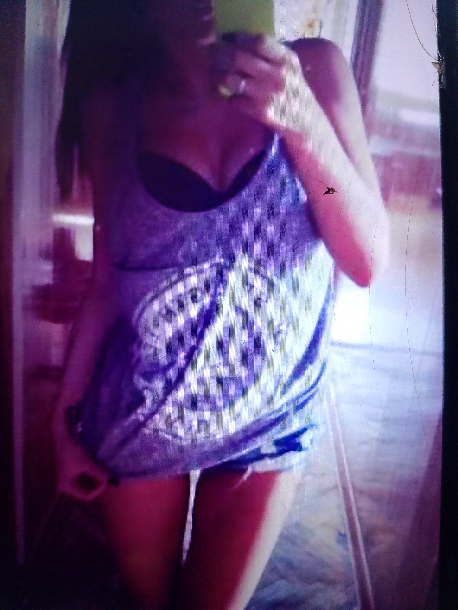 The image shows a person from the chest down, wearing a purple tank top with a graphic design. The person is also wearing dark underwear. The background is blurred and appears to be an indoor setting, possibly a room with purple and pink lighting. There are some vertical lines visible on the image, suggesting it might be a photograph of a screen. The location of Dobra Krynytsia, Ukraine is not ascertainable from the visual information provided in the image.