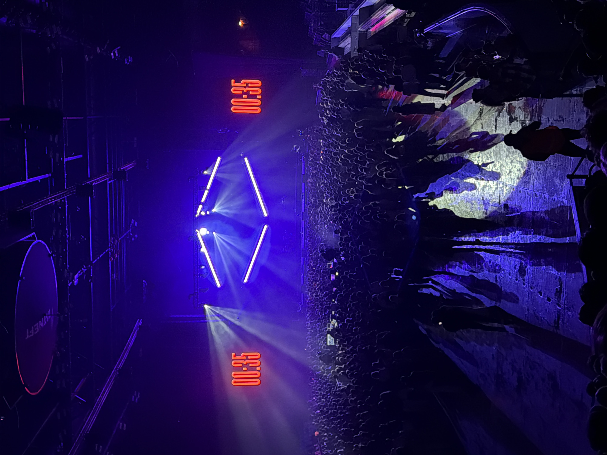 The image shows a live concert with a large crowd of people. The stage has a lighting setup with blue and white beams, and a digital display showing "00:35" in red. A round sign with the word "HAINEFT" is visible on the left. The venue seems to be indoors. The city is Kazan, Russia.