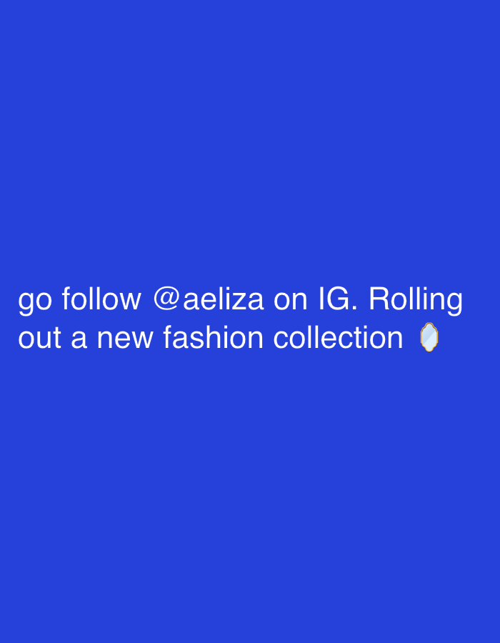 The image displays white text set against a solid blue background. The text reads: "go follow @aeliza on IG. Rolling out a new fashion collection", followed by a small, ornamental mirror emoji. No people are present. The subjects consist exclusively of the textual message and the emoji. There are no additional objects, actions, or interactions depicted. The environment is an undifferentiated field of blue. No visual cues are present to determine a specific geographical location within the city of London, United Kingdom, or elsewhere.