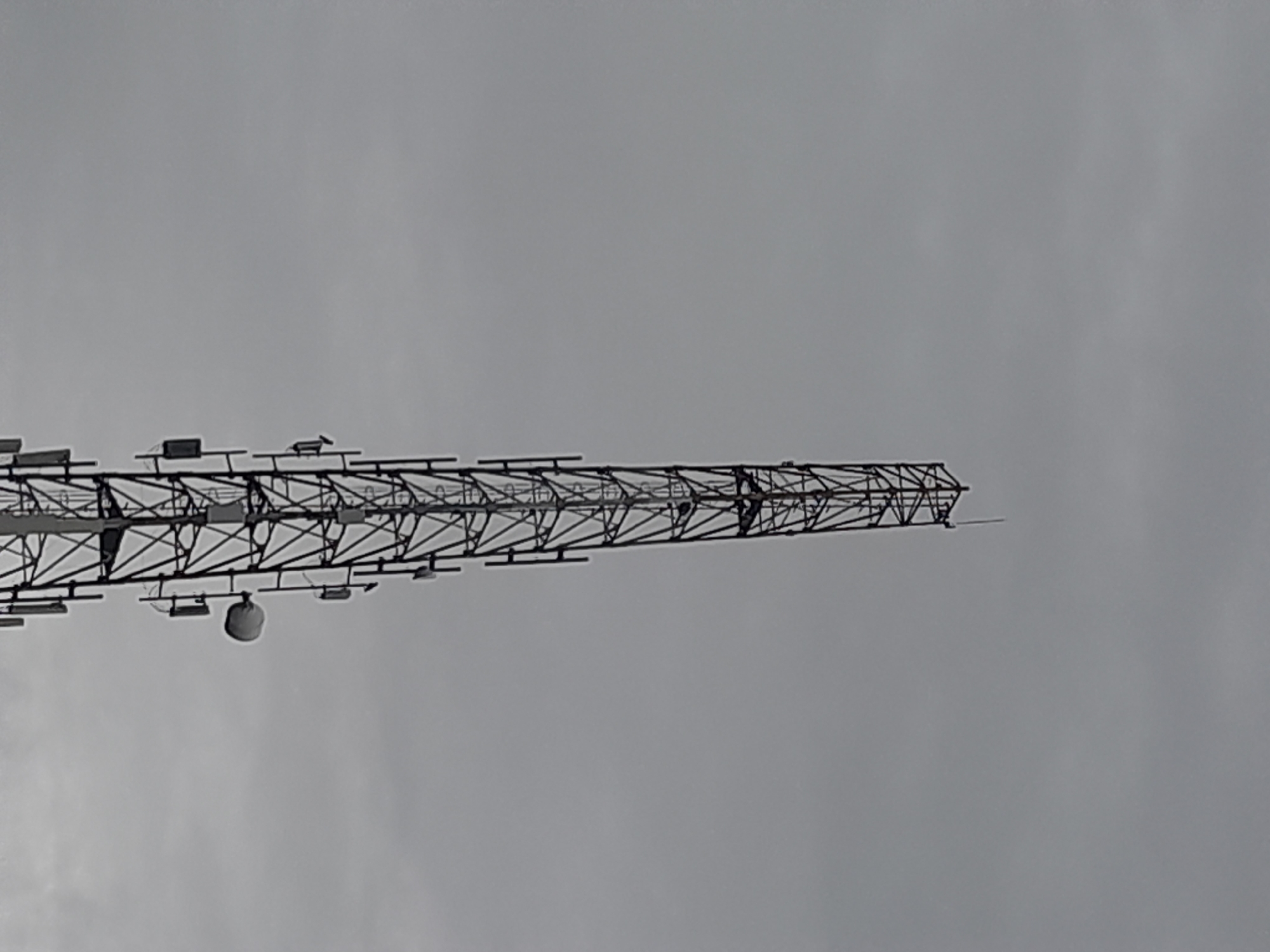 The image shows a metal lattice structure extending horizontally against a gray sky. The structure appears to be a section of a radio or communications tower. It is located in Egbagu, Nigeria. The sky is overcast and featureless. There are no other discernible objects or people in the frame.