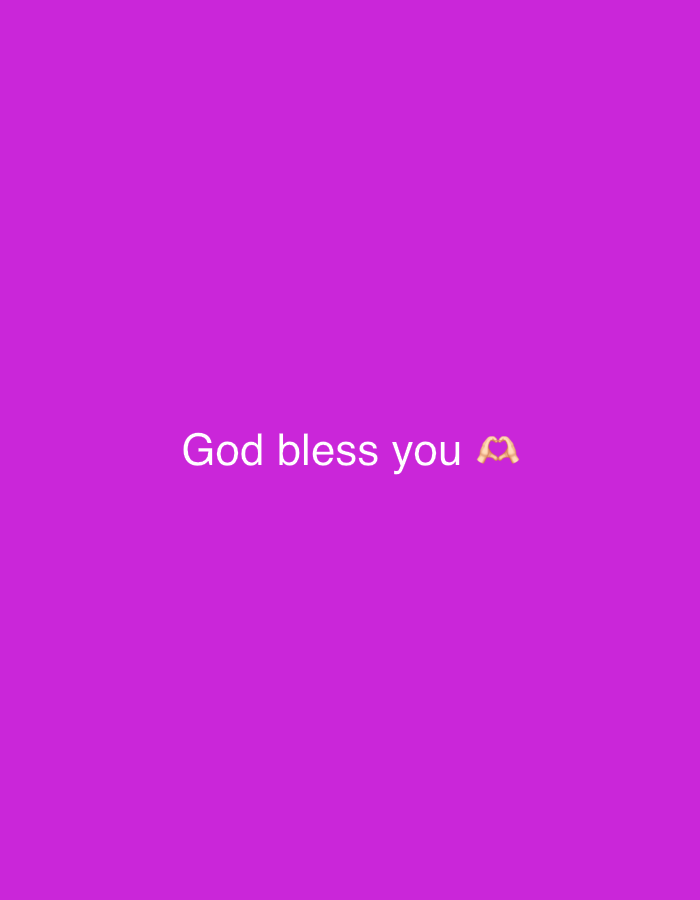 A medium shot captures a vibrant, solid purple background that fills the entire frame. Centered horizontally and positioned towards the bottom of the image are the words "God bless you" in a clean, white, sans-serif font. To the right of the text, a small, yellow heart emoji is displayed, formed by two hands.
