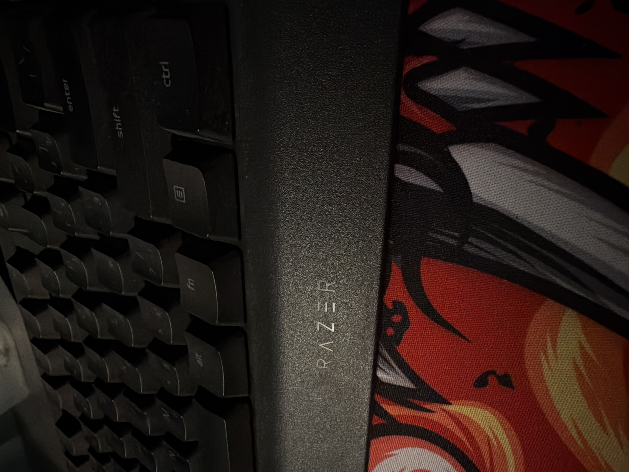 The image shows a close-up of a Razer keyboard and mousepad. The keyboard is black and has the "RAZER" logo on the wrist rest. The keys visible include "enter", "shift", "ctrl", "fn", and "alt". The mousepad has a colorful design with red, yellow, white, and black elements. The image does not contain information about the location in Izhevsk, Russia.