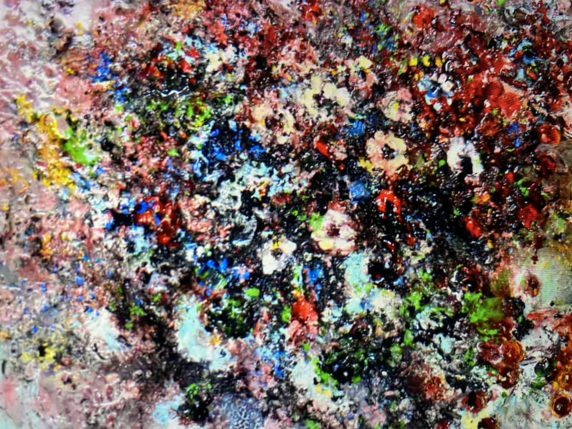 The image is a close-up, abstract painting with a highly textured and colorful surface. The painting features a dense, layered application of paint, creating a mosaic-like effect. Dominant colors include vibrant reds, blues, greens, yellows, and pinks, interspersed with areas of black and white. The texture is rough and uneven, with visible brushstrokes and possibly impasto techniques. Some areas appear glossy, suggesting the use of different paint mediums or varnishes.
The composition is chaotic and organic, with no discernible representational subjects like people, objects, or a specific scene. It is an abstract expression, evoking a sense of energy and complexity. The painting's surface is uneven and appears to be composed of small, irregular shapes and masses of color that overlap and blend into one another. There are no clear indicators of time of day, weather, or specific location. The overall impression is one of a rich, multifaceted, and perhaps energetic abstract artwork. No text is visible in the image.