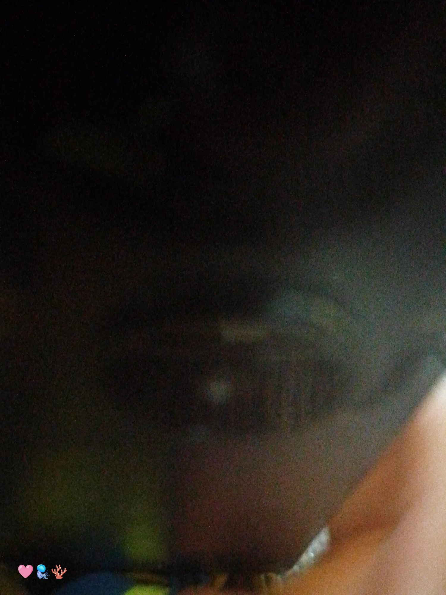 The image is very dark and blurry, making it difficult to discern details. In the foreground, there is a hand with skin visible. The background appears to be dark, obscuring any location or objects that might be present. No specific city or environment can be identified.