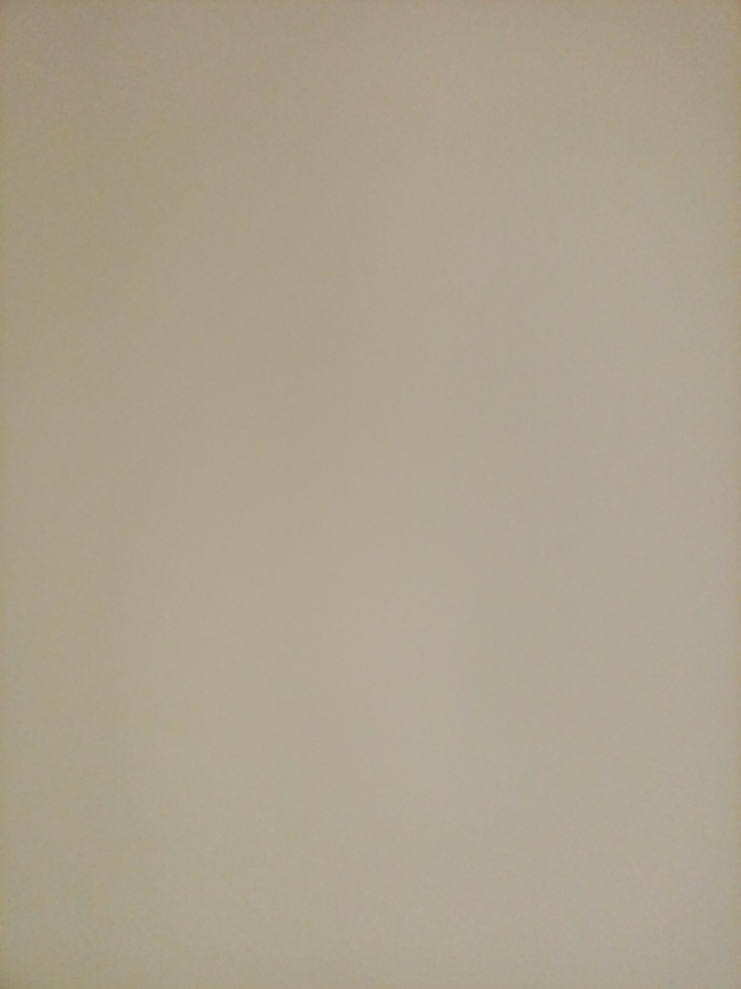 The image is a plain, light beige background with a slightly textured surface. There are no discernible objects, people, or environmental features present in the image. The lighting appears even, with no strong shadows or highlights. The image is entirely abstract, lacking any specific location or context.