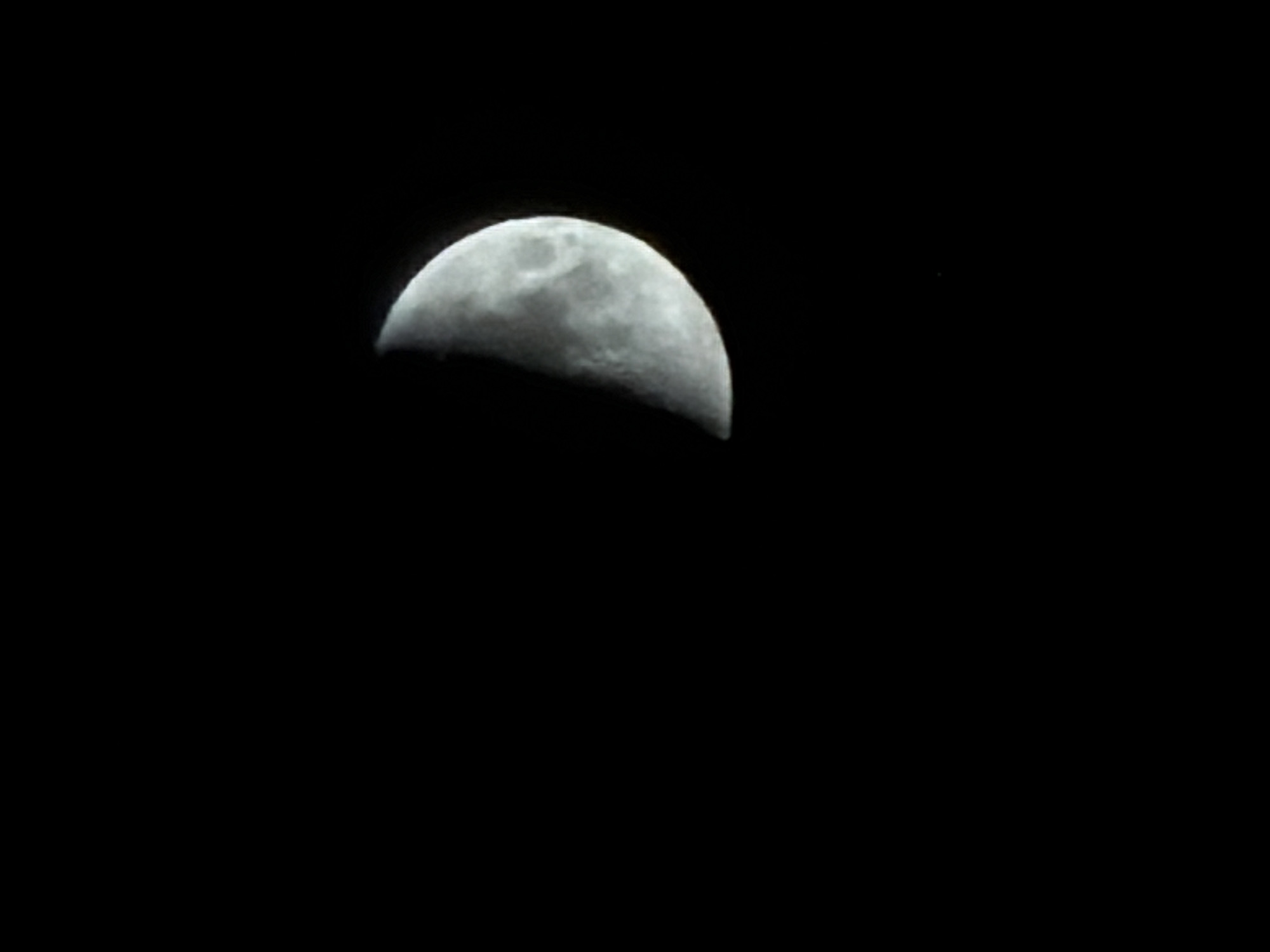 The image shows a crescent moon against a black sky. There is no indication of Izhevsk, Russia, or any urban environment. No people, objects other than the moon, actions, or interactions are depicted. The environment is simply the night sky.