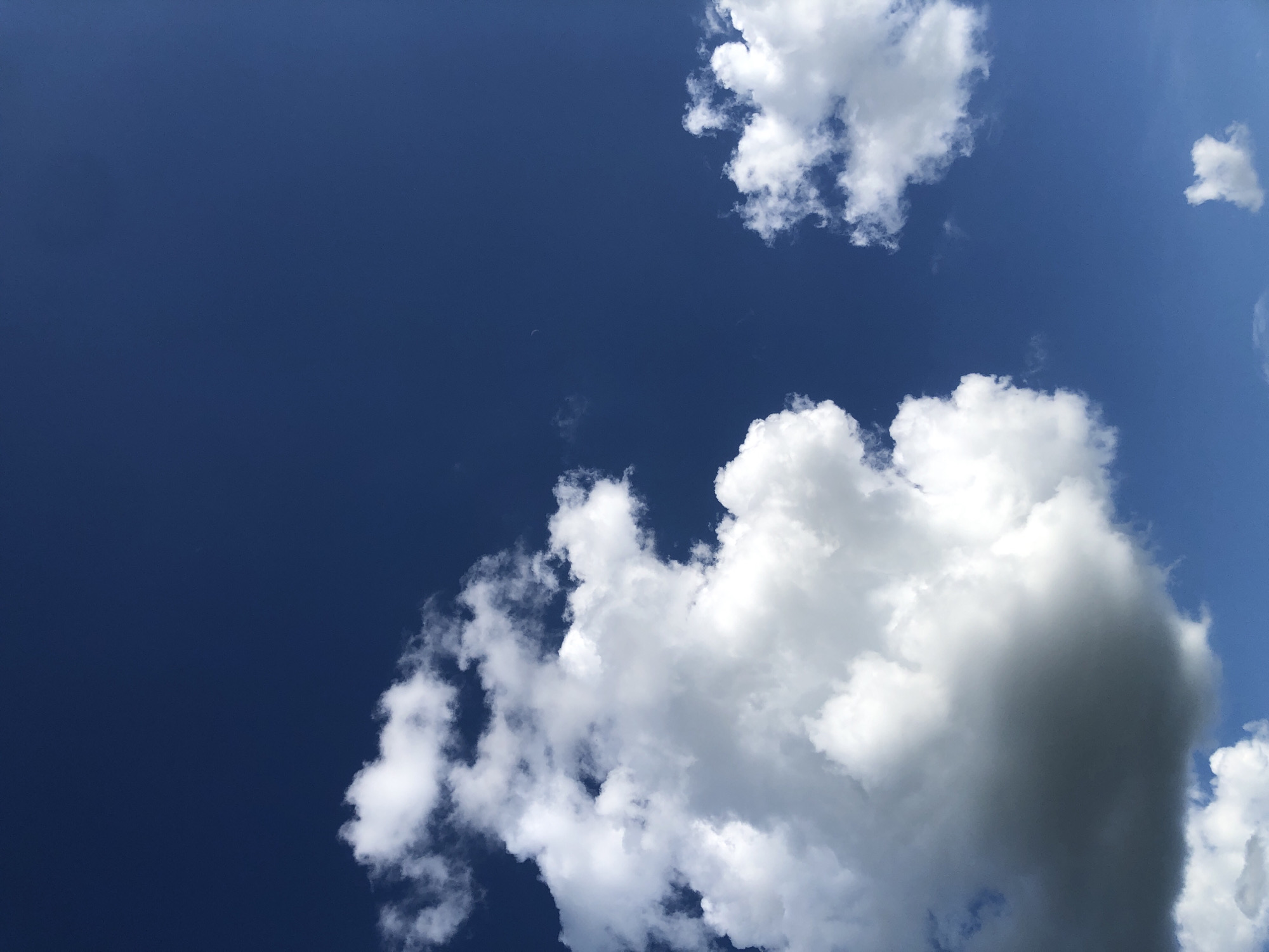 The media file is a photograph of a bright blue sky with several white clouds scattered across it. The clouds vary in size and shape, with some appearing fluffy and well-defined, while others are wispy and thin. The sky is clear and the sun is shining, suggesting it is daytime. There are no people or objects visible in the frame, only the sky and clouds. The overall scene is serene and peaceful, with the vast expanse of the sky evoking a sense of openness and freedom. The image does not contain any visible text. Given the provided location context of Khmilnytsia, Ukraine, the image likely depicts a typical daytime sky in that region. The weather appears to be fair and sunny.