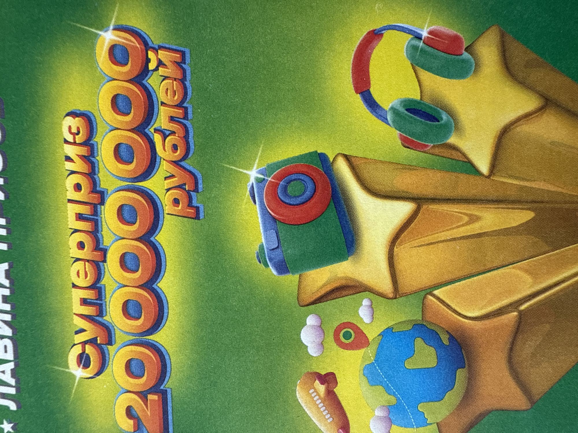 The image shows a promotional graphic, likely from a lottery or competition, with cartoonish depictions of prizes. The text reads "Суперприз 2000000 рублей," which translates to "Super Prize 2,000,000 rubles." This likely indicates the top prize amount.
The graphic features cartoon illustrations of potential prizes, including headphones, a camera, and a globe. These items are surrounded by golden stars. The overall color scheme is predominantly green and gold.
No information is available in the image about the location in Votkinsk, Russia. It may be an advertisement or poster located there, but this cannot be confirmed from the image alone.