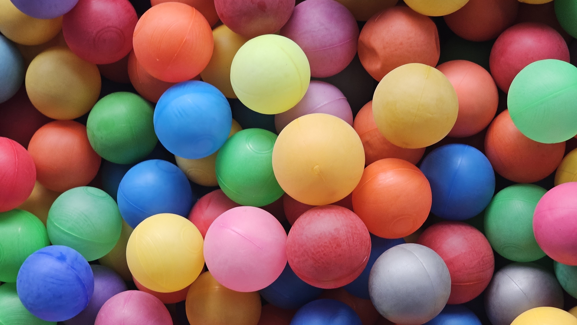 The image depicts a densely packed collection of colorful plastic balls. The balls are various shades of blue, green, yellow, orange, pink, red, purple, and gray. The composition is an overhead shot, completely filling the frame with the balls. There is no clear indication of the location being San Bernardino Tlaxcalancingo, Mexico, or any other identifiable location. No people, actions, or interactions are visible.