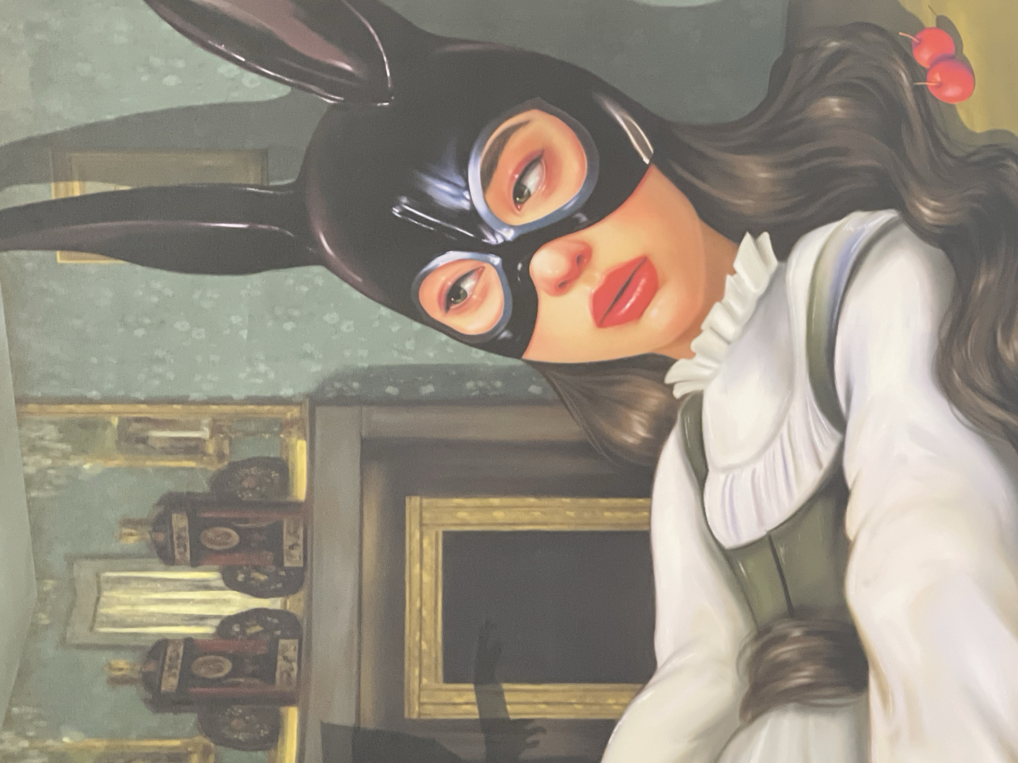 A painting depicts a woman wearing a black bunny mask. The woman has brown hair with two red cherries attached. She is wearing a white dress and a green bodice. The background features floral wallpaper, paintings, and furniture. The city and location are not discernible from the visual elements of the image.