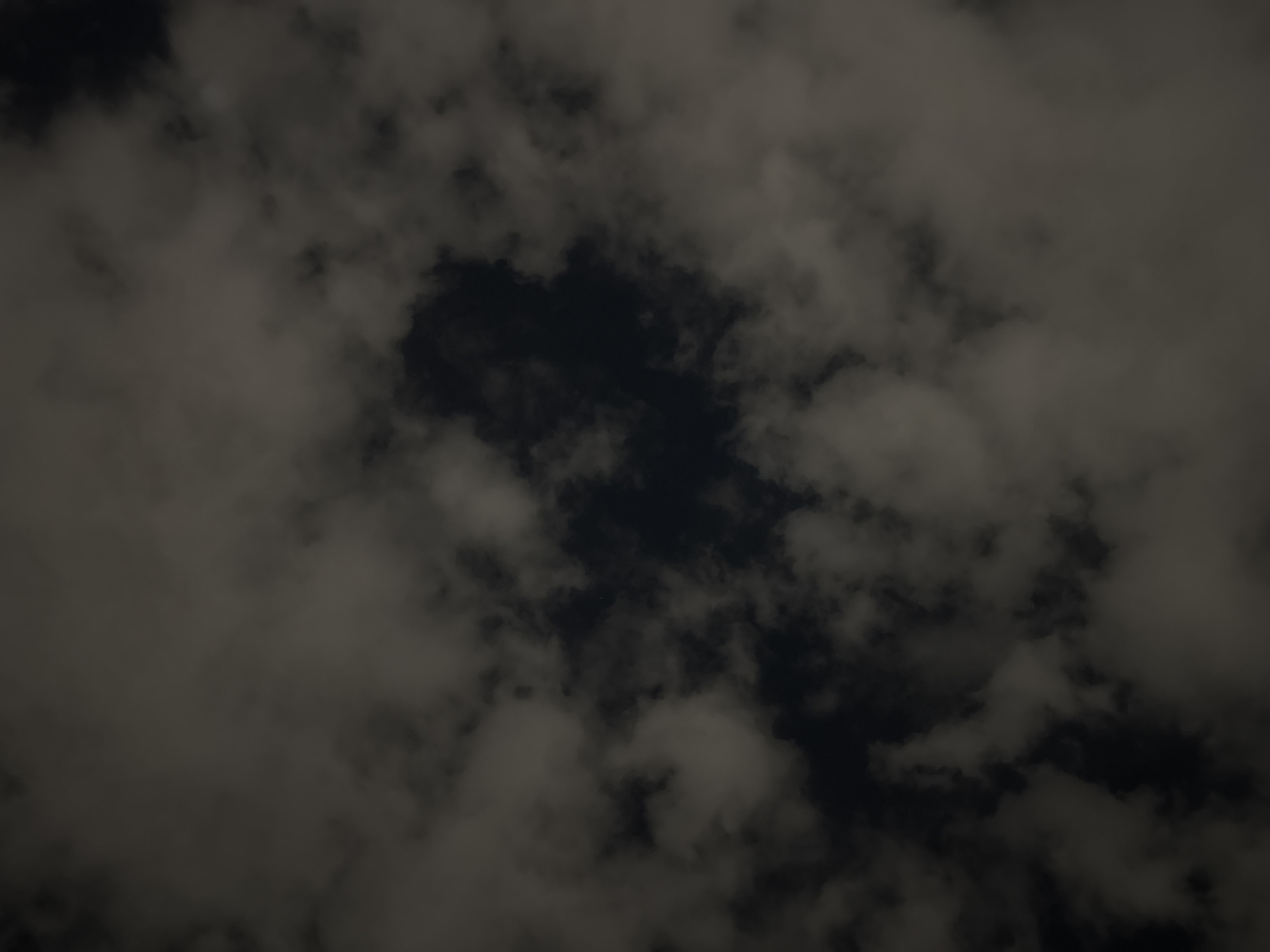 The image depicts a dark, cloudy sky. The clouds are dense and gray, with patches of darker sky visible in between. There are no discernible people, subjects, objects, actions, or interactions in the image. It's impossible to determine the specific location in Puebla, Mexico, based on this image alone.