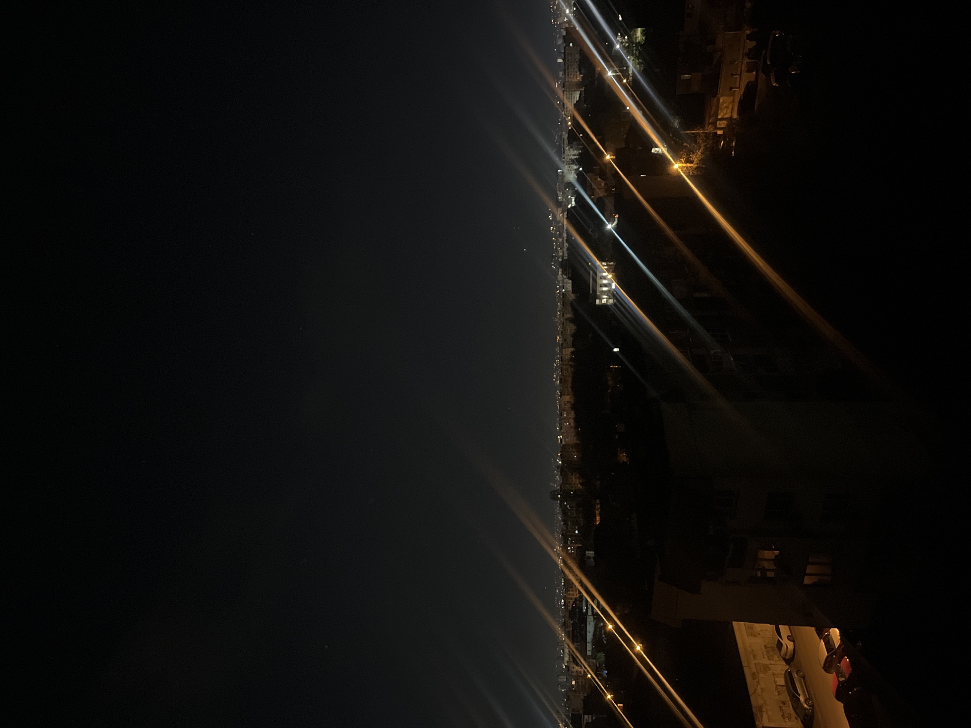 The image shows a night view of a city, with streetlights and buildings lining the horizon. The horizon is slightly offset from the center of the image. Light streaks across the image, originating from streetlights and buildings. The location is likely Sofia, Bulgaria.