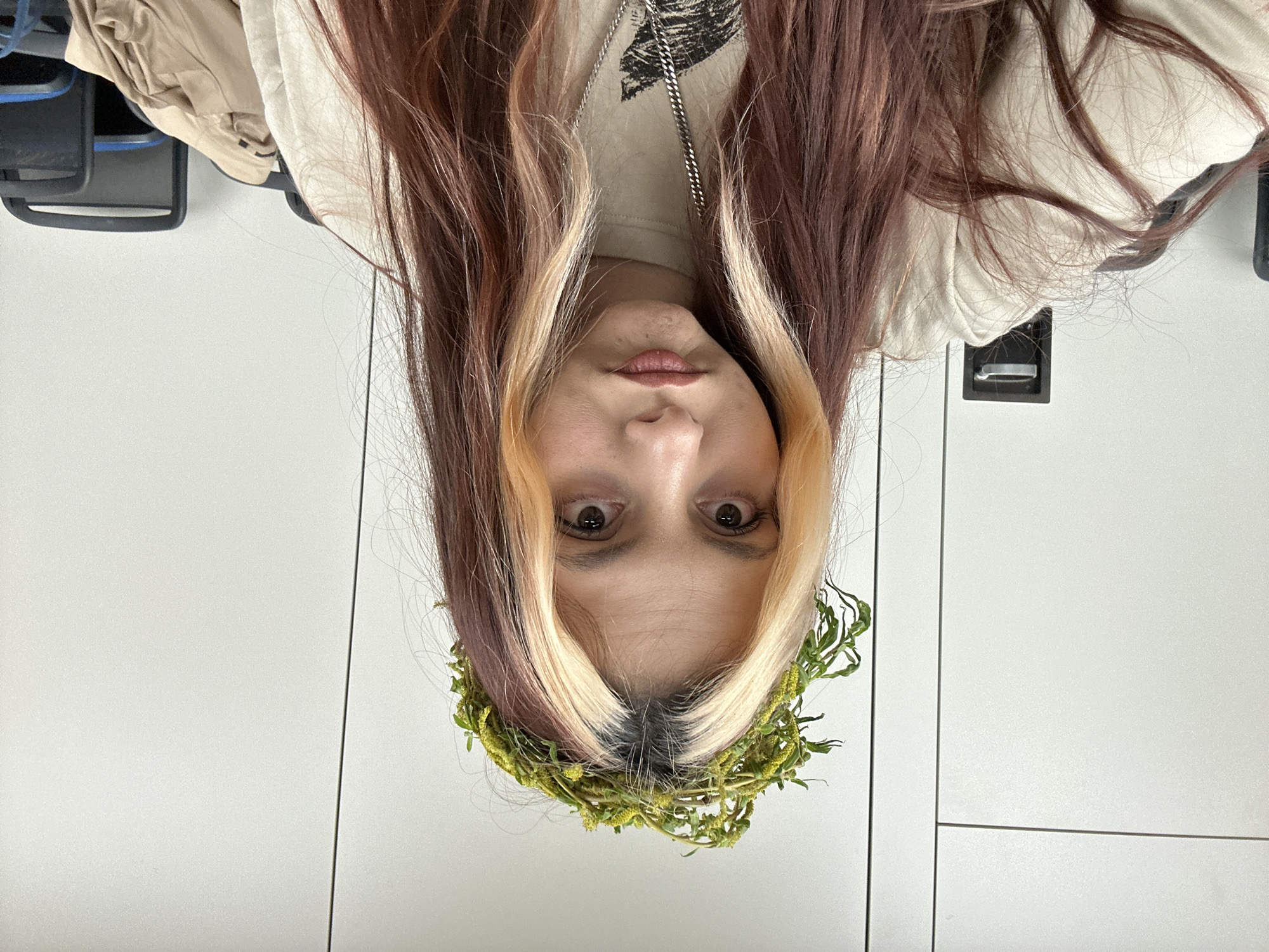 A person with highlighted brown and blonde hair, wearing a floral crown, is facing the camera. The background appears to be a white tiled wall. The photo was likely taken indoors. There is no information available to determine if the picture was taken in Sofia, Bulgaria.