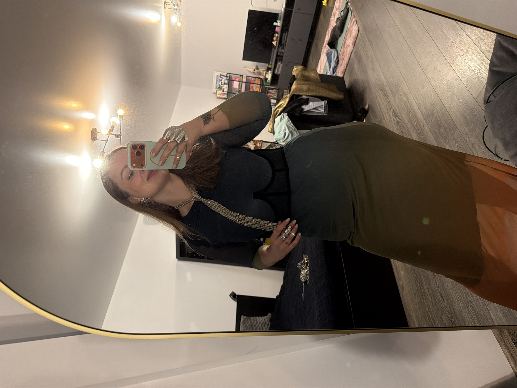 A woman is taking a selfie in a mirror. The background includes a living room setup with a TV, furniture, and decorations. The location is not identifiable as Moscow, Russia.
