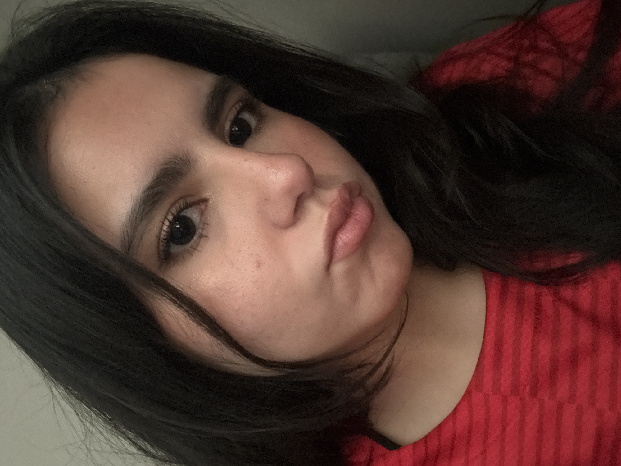 A close-up portrait depicts a woman with dark hair, brown eyes, and a fair complexion. She is wearing a red, vertically striped shirt. Her lips are slightly pursed. The background is indistinct. It is not possible to determine her location within College Station, United States of America based solely on this image.