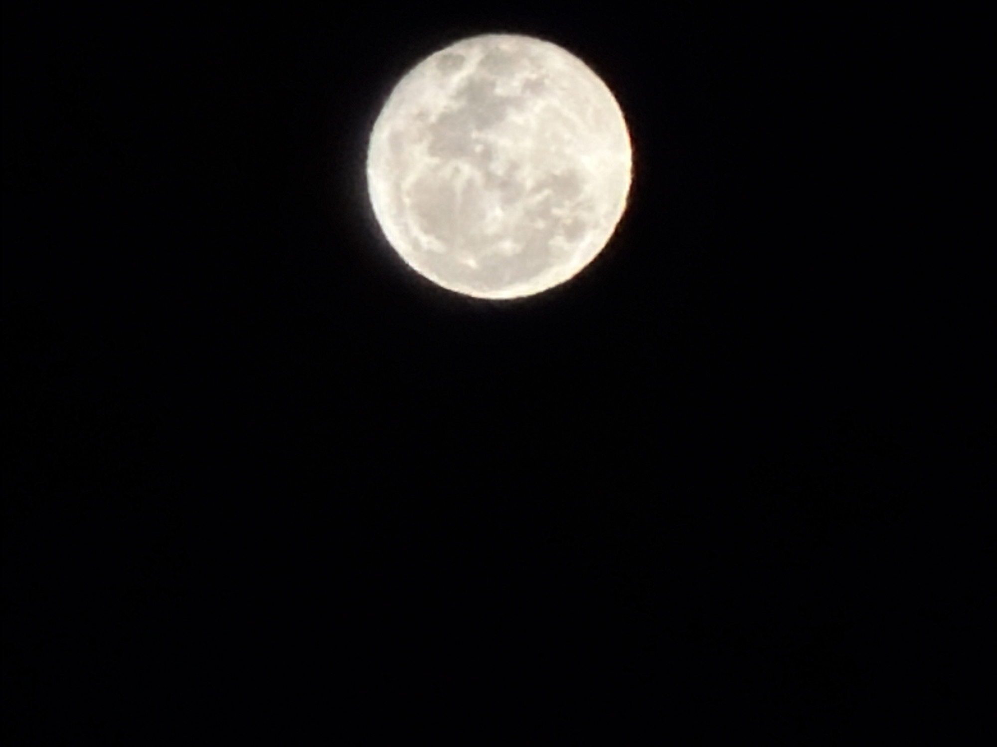 A full moon is prominently displayed against a black background. The moon exhibits detailed surface features. The location and city details are not discernible from the image.
