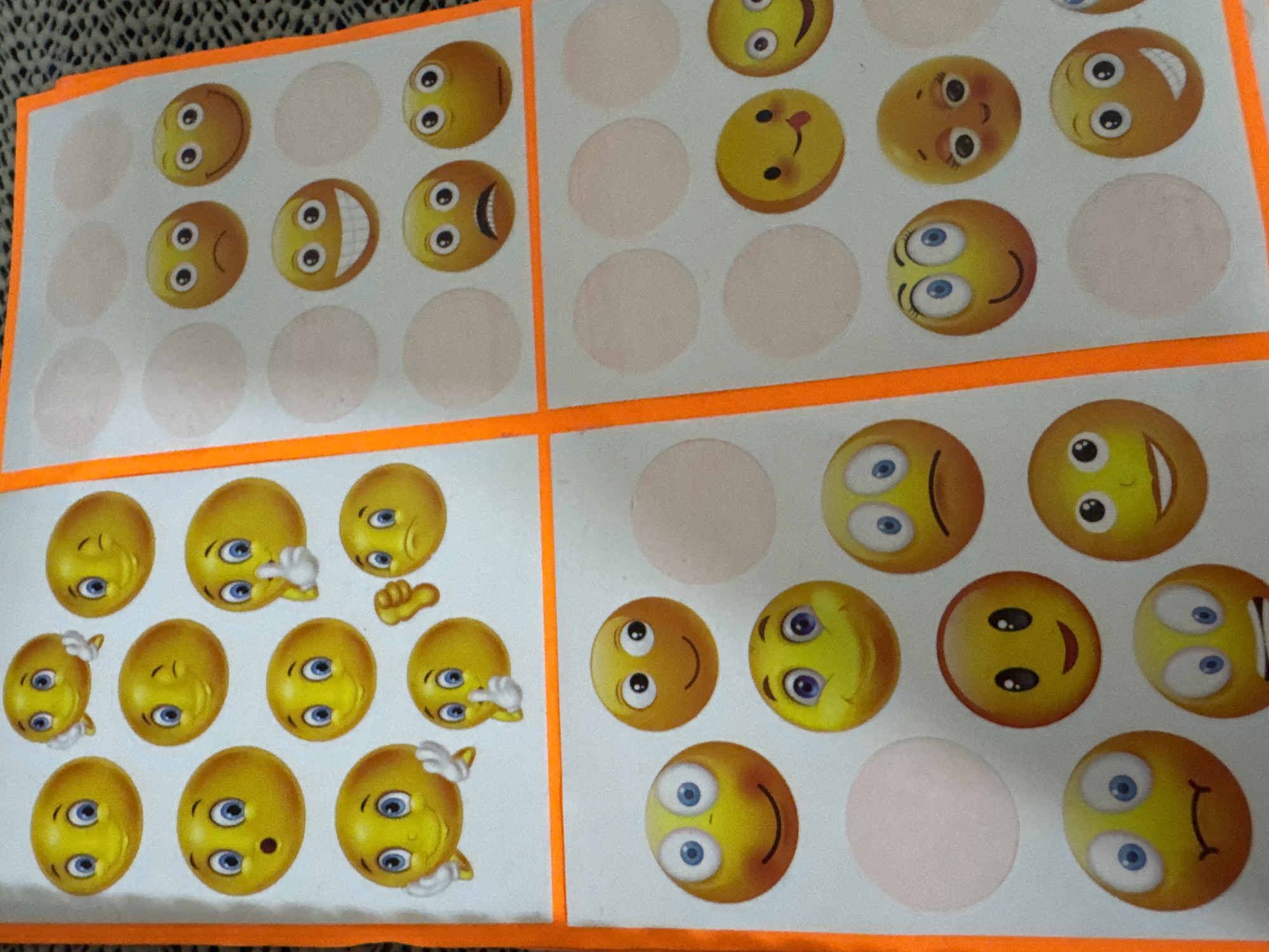 The image shows four quadrants of a white sheet, each quadrant bordered by orange tape. Each quadrant contains a grid of circular spaces, some filled with cartoon smiley faces and some left blank. The smiley faces vary in expression, some are upside down, and some have additional elements like hands. The image was not taken in Sofia, Bulgaria; this is inferred from the image content.