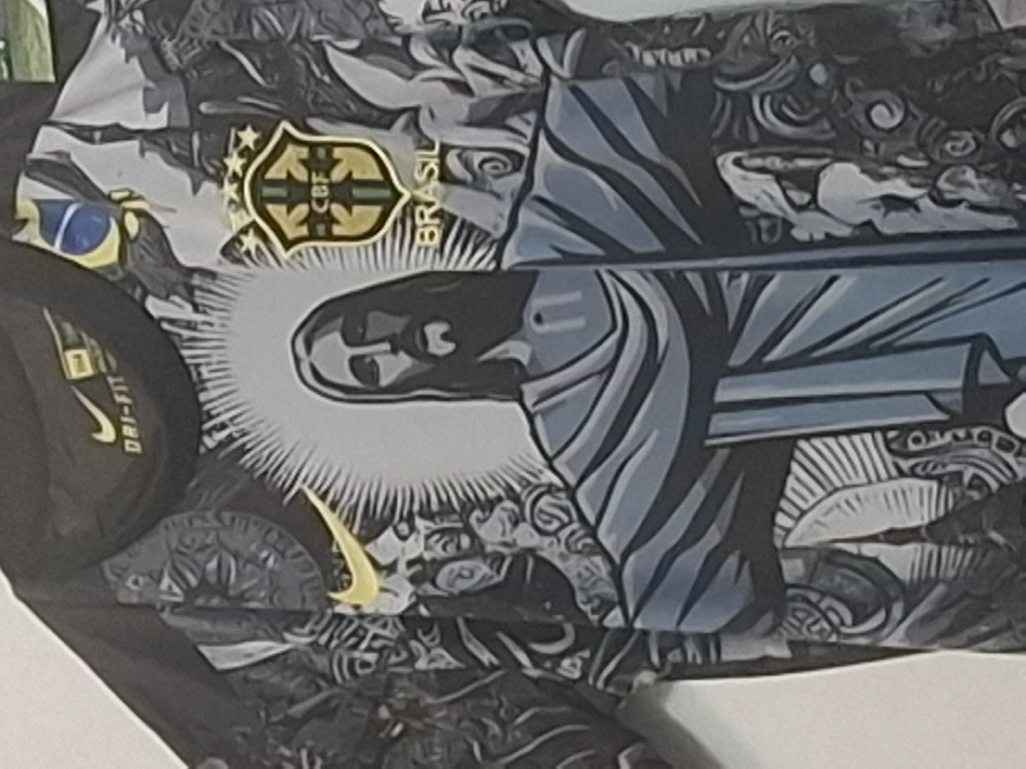The image displays a dark-colored t-shirt, likely made of performance fabric, hanging vertically against a plain light background. The central design prominently features an illustration of Jesus Christ with outstretched arms, akin to the Christ the Redeemer statue, surrounded by a radiating white halo. His robes are rendered in blue-grey and darker grey tones. To the upper left, a yellow Nike swoosh logo is visible, accompanied by "DRI-FIT" text. To the upper right, a gold shield emblem of the Confederação Brasileira de Futebol (CBF) is displayed with five stars above it and the word "BRASIL" below. A partial Brazilian flag motif is also present near the CBF logo. The entire background of the t-shirt is covered in an intricate, monochrome pattern of dark and light grey abstract and stylized figures. The location is in the city of Isperih, Bulgaria.