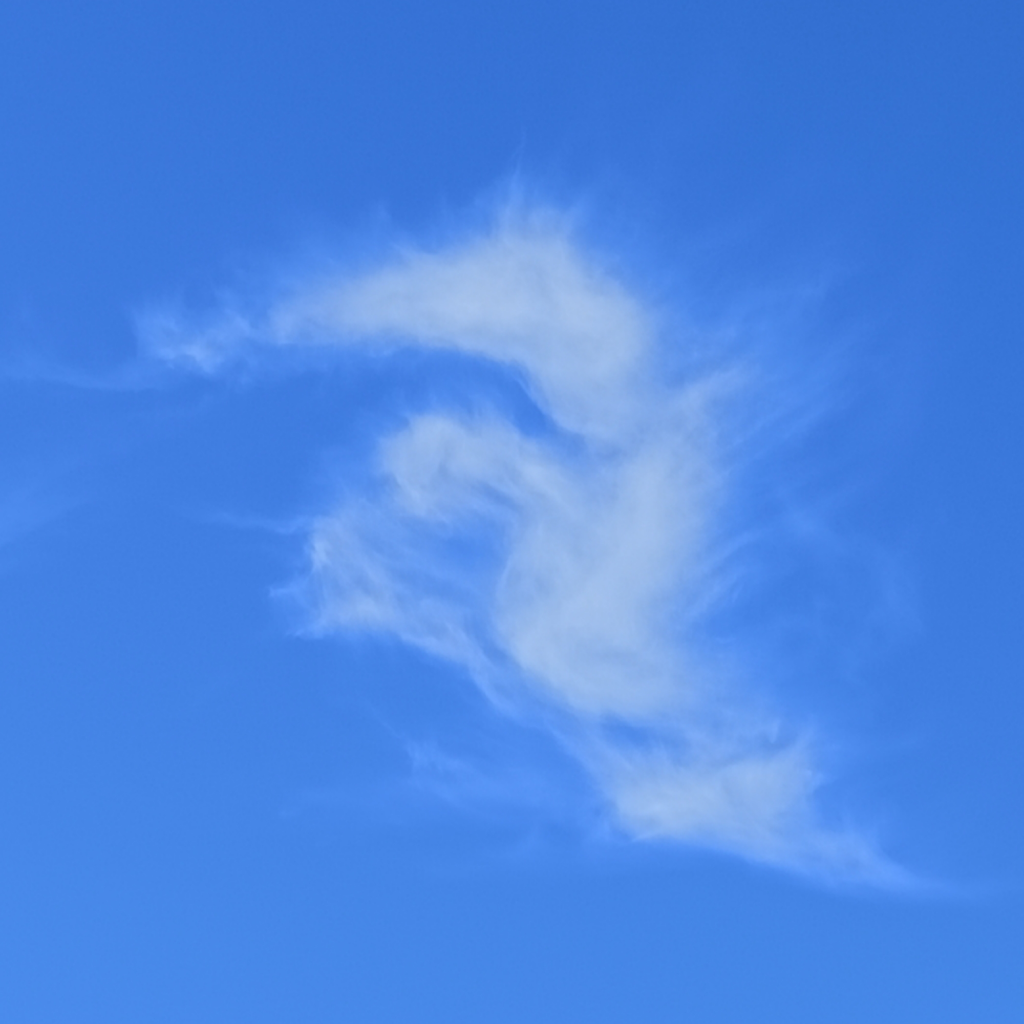 This is a photograph of a blue sky with wispy white clouds. The clouds are scattered and appear to be cirrus clouds. There are no people, buildings, or other objects visible in the image. The photograph was taken from Ballybunnion, Ireland.