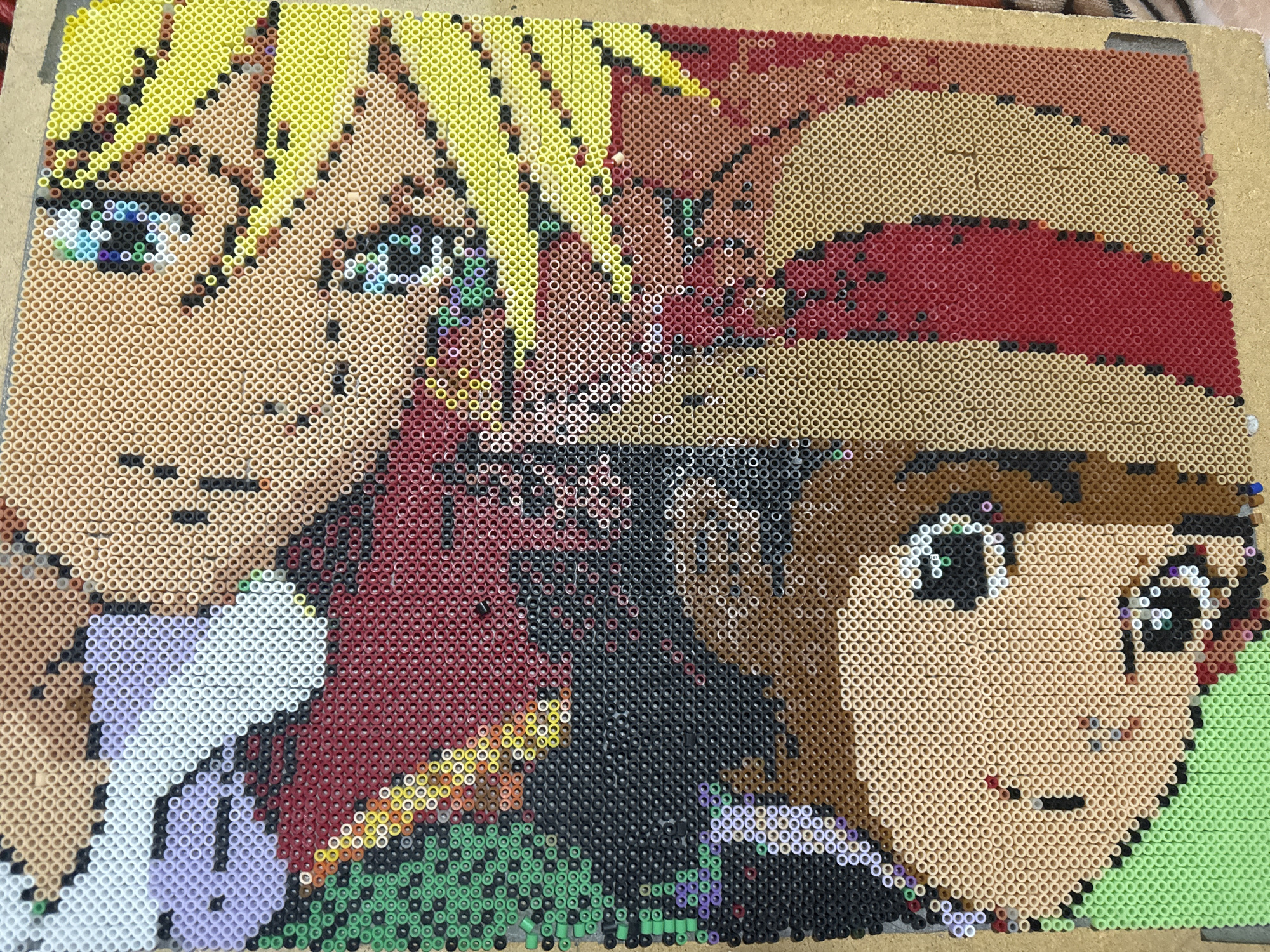 A homemade pixel art image created with Perler beads or similar fuse beads. The picture depicts two anime-style characters, possibly fan art.
Character 1: Located on the left side, has blonde, spiky hair (rendered in bright yellow beads), fair skin (in light tan beads), and bright eyes with a mix of blue, green and white beads to give a sparkling effect. The character wears a white shirt with a purple-grey collar, represented in beads.
Character 2: Positioned on the right, the figure has light brown skin, a medium-brown hair color, and similar anime-style eyes. The subject is wearing a red hat with a beige/tan brim, also created out of the plastic beads.
The background is filled with various colored beads: black, red, green, and dark brown.
There is no data to indicate that this image was taken in Puebla, Mexico.