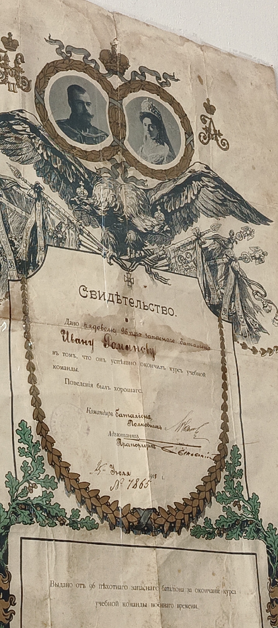 The image is a certificate of completion, issued to a Private Ivan Romanov of the 96th Reserve Battalion. The certificate states that Romanov successfully completed the course of the training team. The certificate is dated July 4, 1915, and numbered 7865. It is signed by the Battalion Commander, a Colonel, and the Adjutant, a Second Lieutenant with what appears to be a signature of "Bilogin." The certificate was issued by the 96th Infantry Reserve Battalion upon completion of the wartime training team course. The certificate features an image of Tsar Nicholas II and Tsarina Alexandra, as well as the Imperial Eagle. The certificate appears old and weathered. There is no mention of Kemul, Russia on the document.