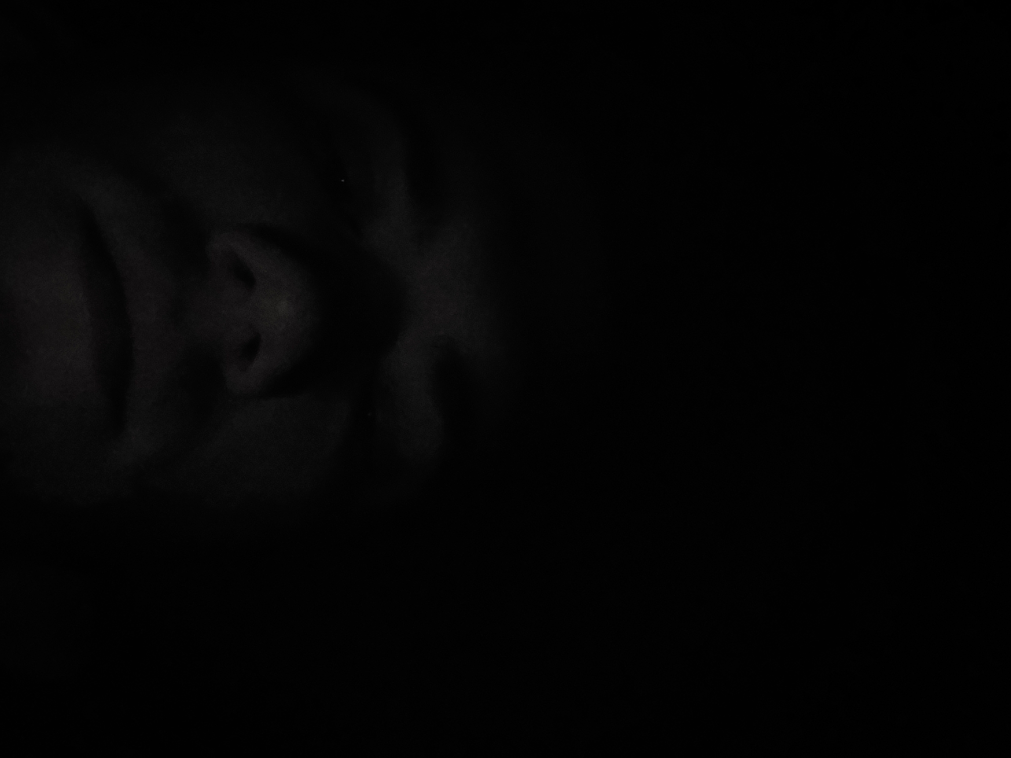A close-up, dimly lit image features the face of a person. The face is slightly rotated, positioned on the left side of the frame. The darkness obscures many details, but the nose and some facial contours are discernible. The background is completely black. There is no information available in this image to determine if it was taken in the city of Tashkent, Uzbekistan.